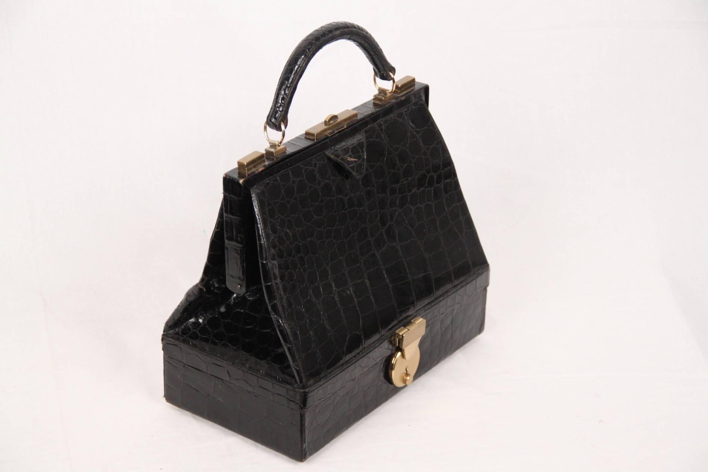 - Vintage black Crocodile structured handbag with bottom compartment
- The bag was particularly favored by wealthy women in the 1950s and 1960s who, when traveling, could carry their fine jewelry with them
- Upper push closure + double side