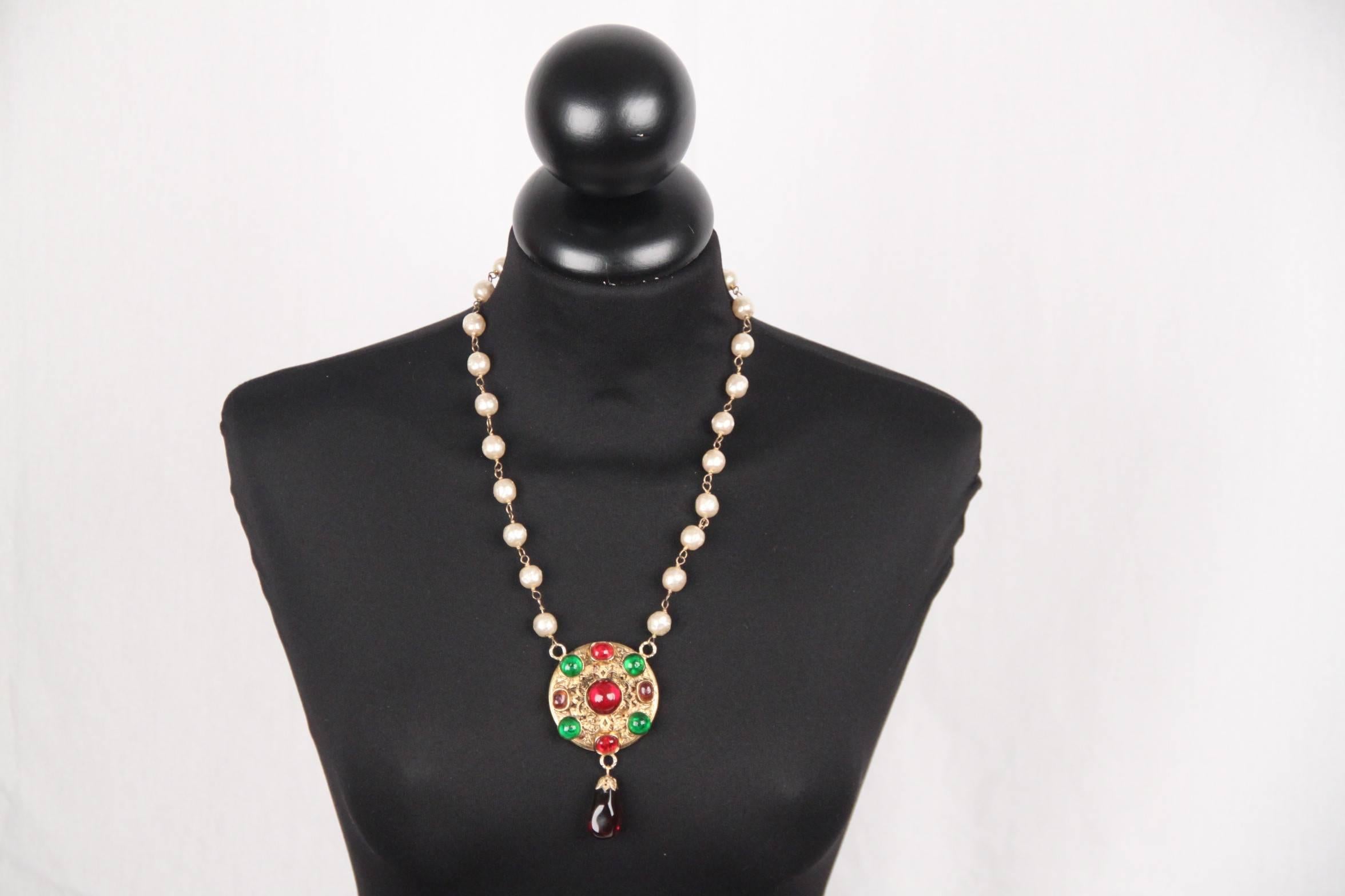 
- Chanel necklace from the 1985
- Glass pearl beads necklace
- Round medallion in the center in gold metal decorated with Gripoix vitreous paste cabochons in red, green and mauve colors
- 1 dangling tear drop pendant  at the bottom of the medallion