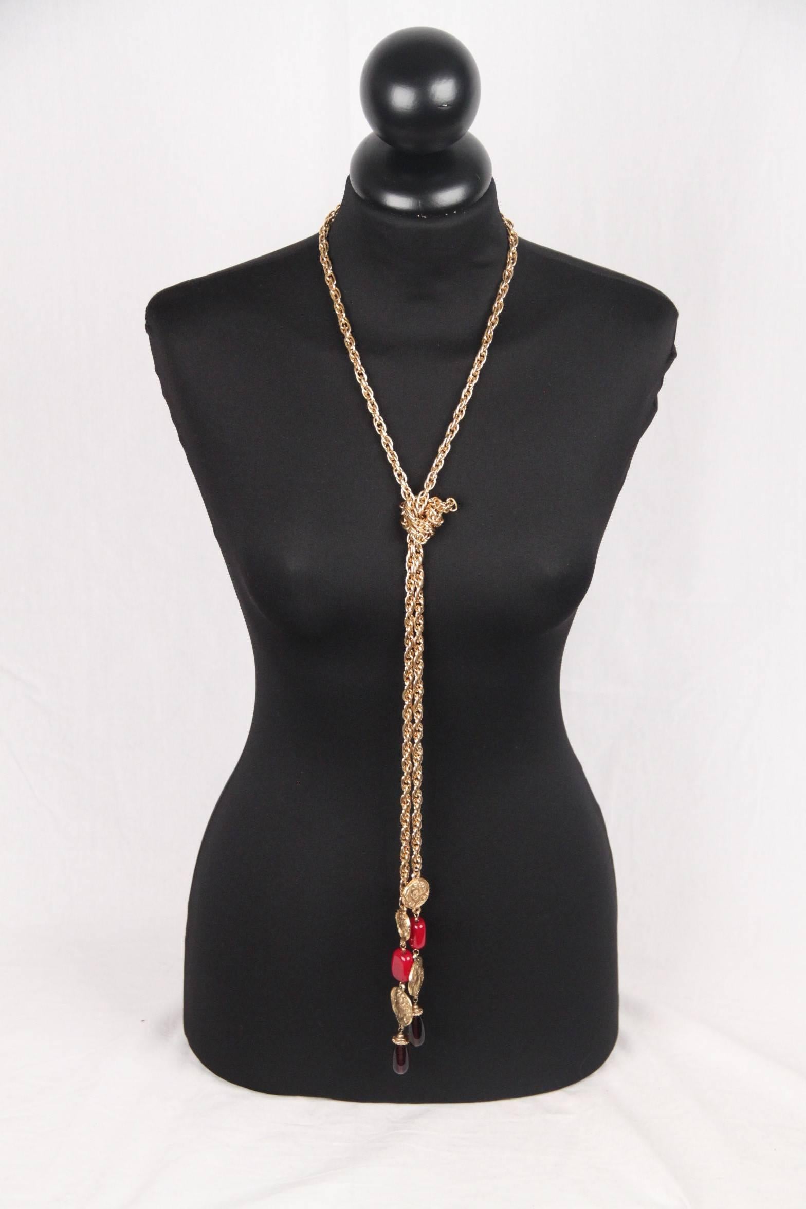 
- Period/ Era: Circa 1971-1980
- Long tie up necklace / Cravatte design
- Gold metal chain finished by embossed medals with embossed heads on a side and CHANEL logo & signature on the other side
- Red and mauve glass beads
- Can be worn in 2