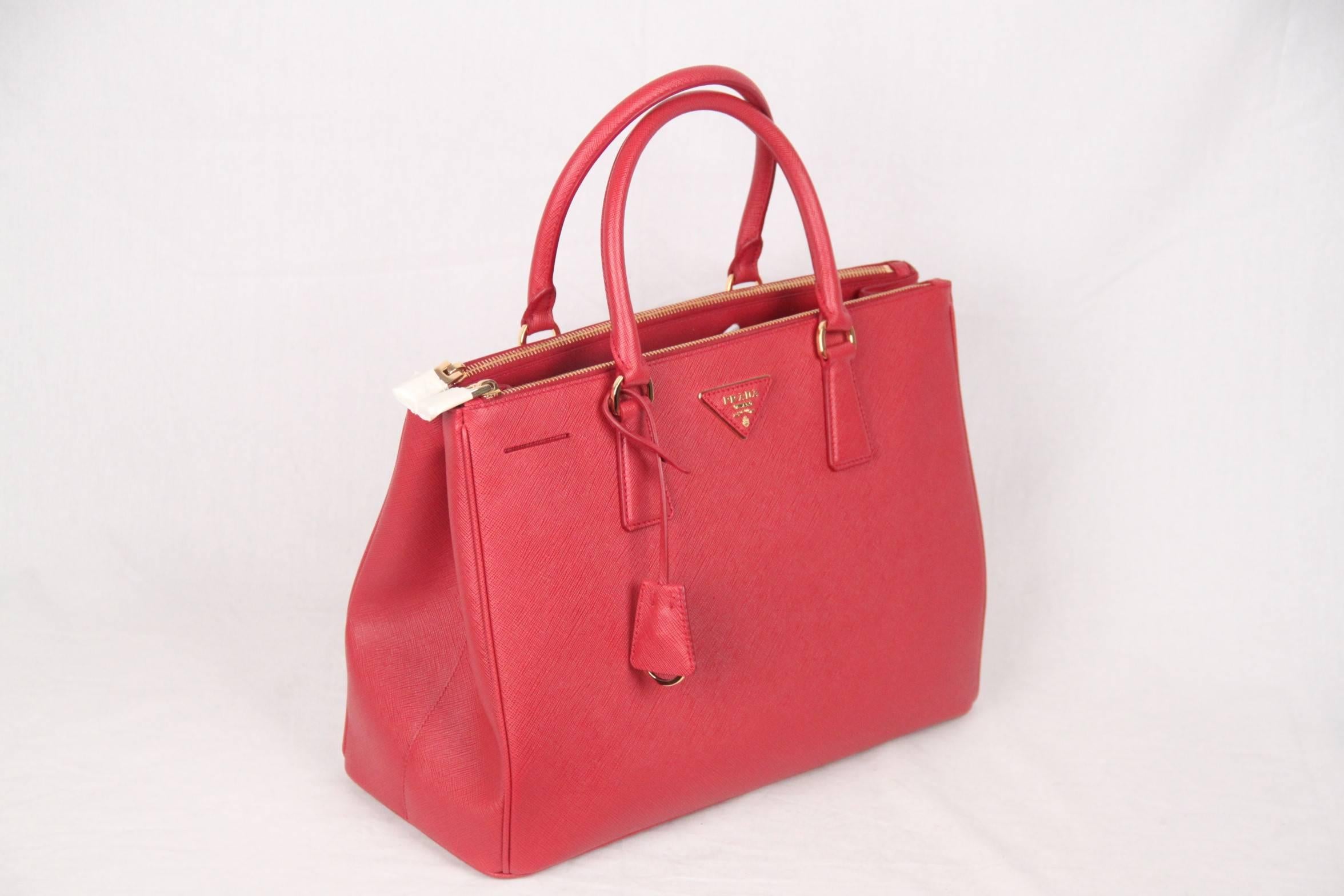 Stunning PRADA top handles bag/handbag mod. 1BA274, designed in red Saffiano Lux leather and finished with leather traingle logo on the front, all in a structured tote silhouette. It features a removable keychain with leather clochette, double round