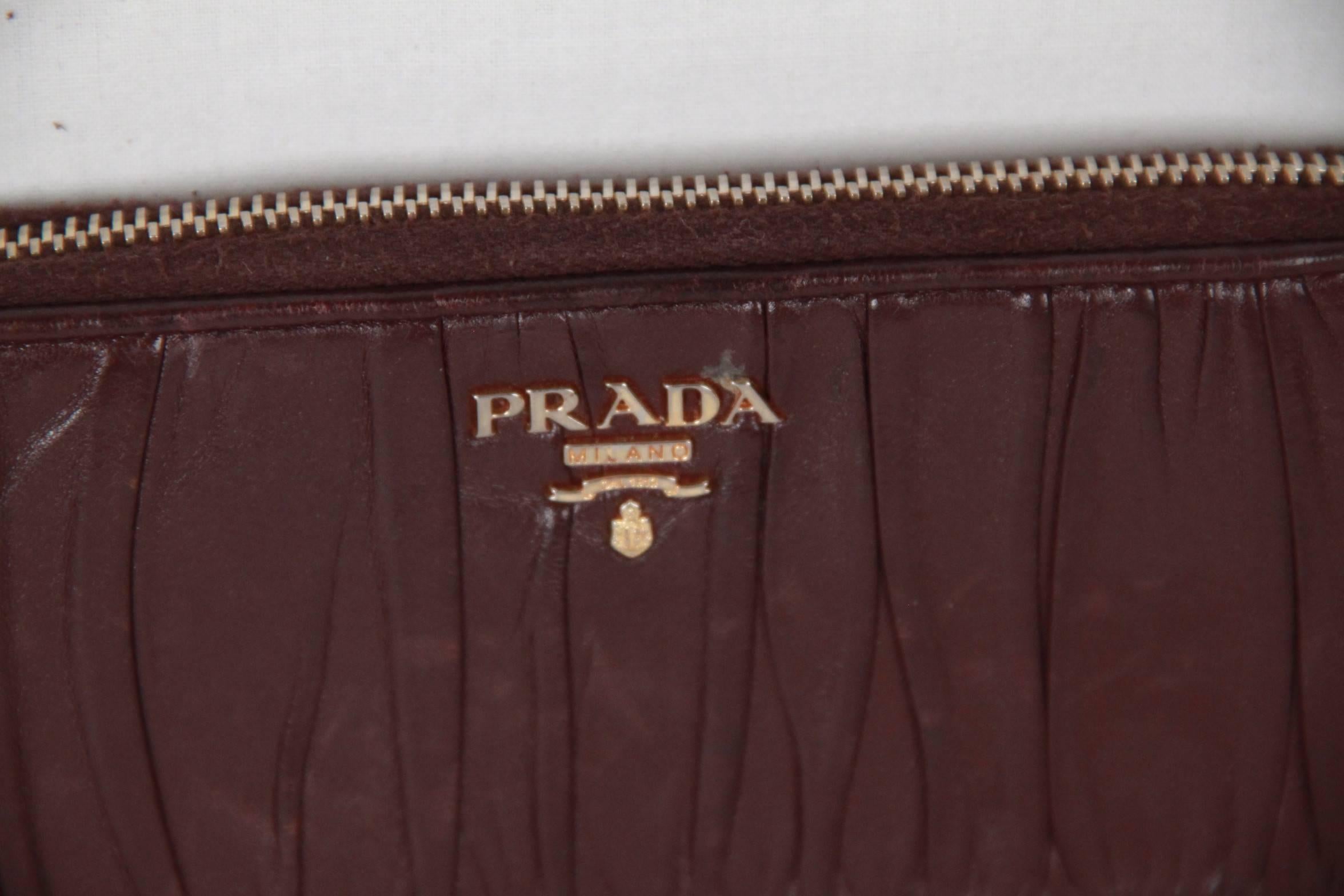 Prada 'Nappa Gaufre' zip around wallet with gold plated hardware. Ruched lambskin with PRADA logo lettering. Zipper closure. 1 coin compartment with zip closure. Eight credit card slots. Two billfold compartments. Made in Italy

Logos & tags: