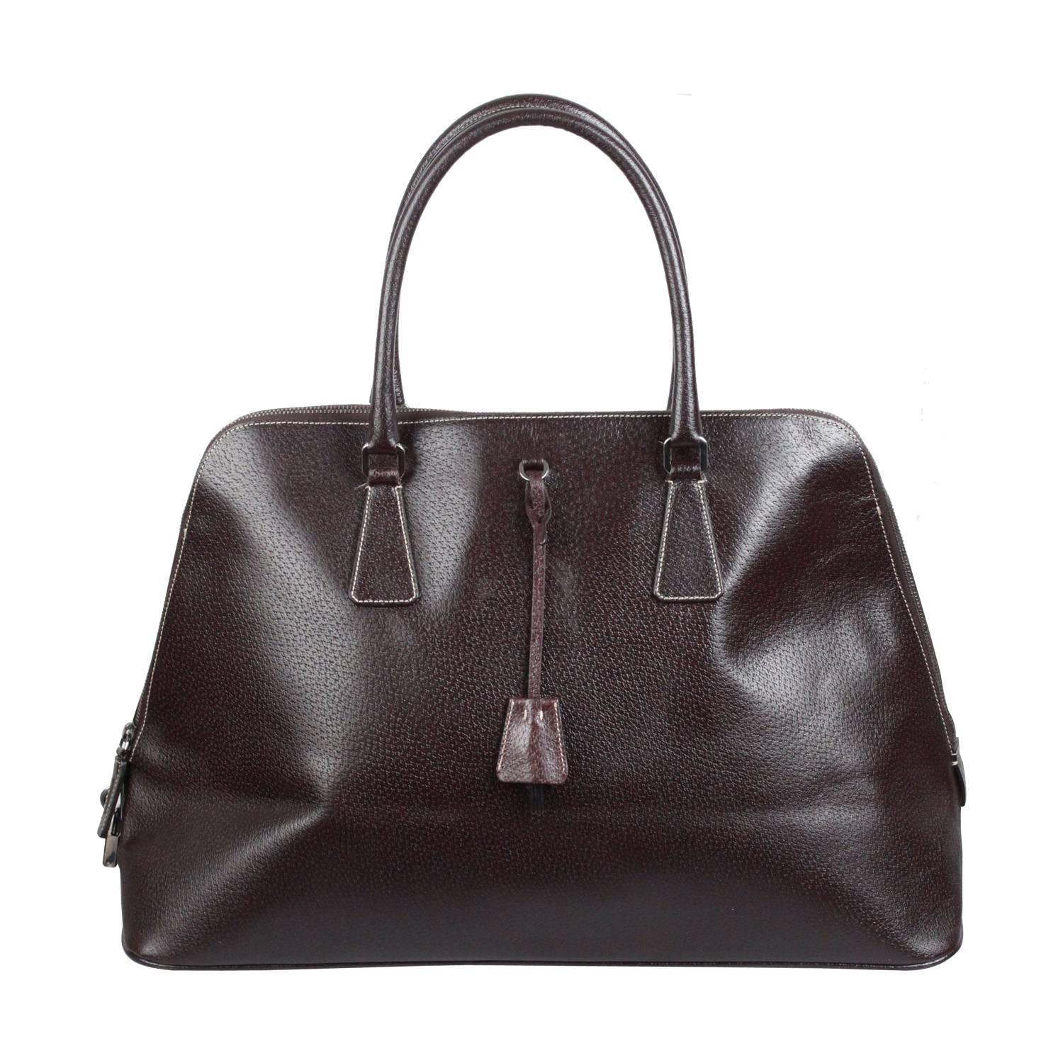 - Prada large Bowling bag  
- Crafted in brown leather 
- Features double top handles 
- Upper zipper closure
- Original padlock and key included
- Iconic Prada traingle logo on the front
- Protective base studs 
- Silver-tone hardware accents
-