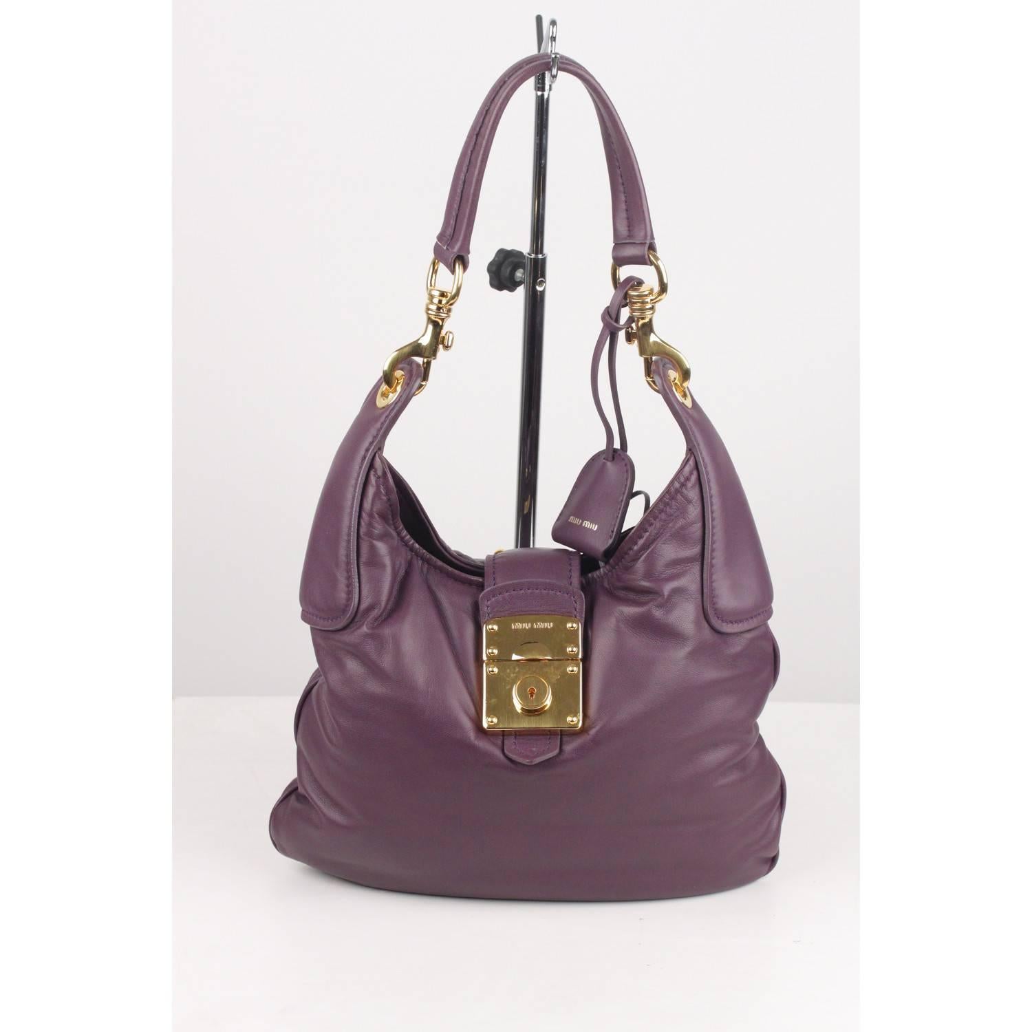 - Purple leather Miu Miu Hobo
- Fold over strap with slide closure
- Gold metal hardware
- Purple satin lining
- 'MIU MIU' logo engraved on the front
- 'MIU MIU - Made in Italy' tag inside
- Small tag with number inside the internal pocket
