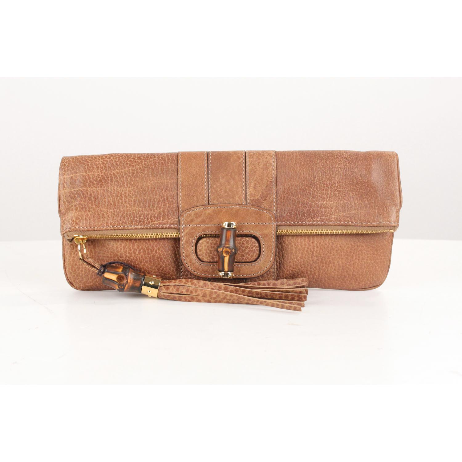 - Gucci 'Lucy' clutch bag in Tan leather
- Gold metal hardware
- Leather tassel detailing
- Bamboo accents
- Folding design
- Twist closure on the front
- Canvas lining
- 'GUCCI - Made in Italy' tag inside (with serial number on its reverse