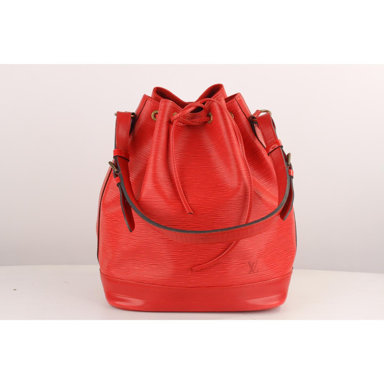 Iconic NOE' by LOUIS VUITTON was first created in 1932 to carry champagne bottles. Red Epi Leather with smooth leather trim, with drawstring closure and Leather and microfibrer lining. 1 side zip pocket inside, Adjustable shoulder strap

Logos /