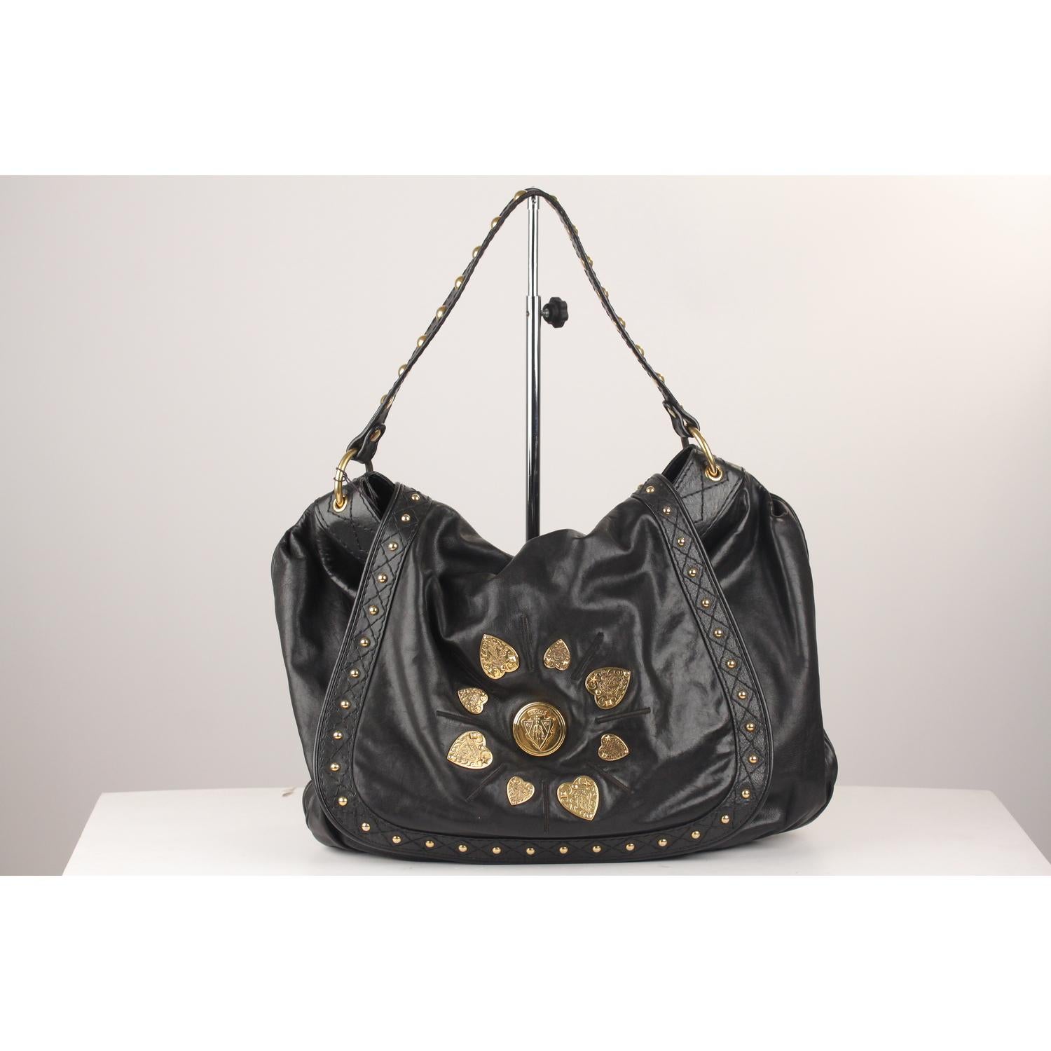 Gucci 'Irina Babouska' Shoulder Bag vrafted from smooth black leather. The bag features Gucci crest medallions on the flap sorrounded by heart-shaped Gucci crests. Studs detailing on the flap and on shoulder strap. Flap closure. Black Gucci fabric