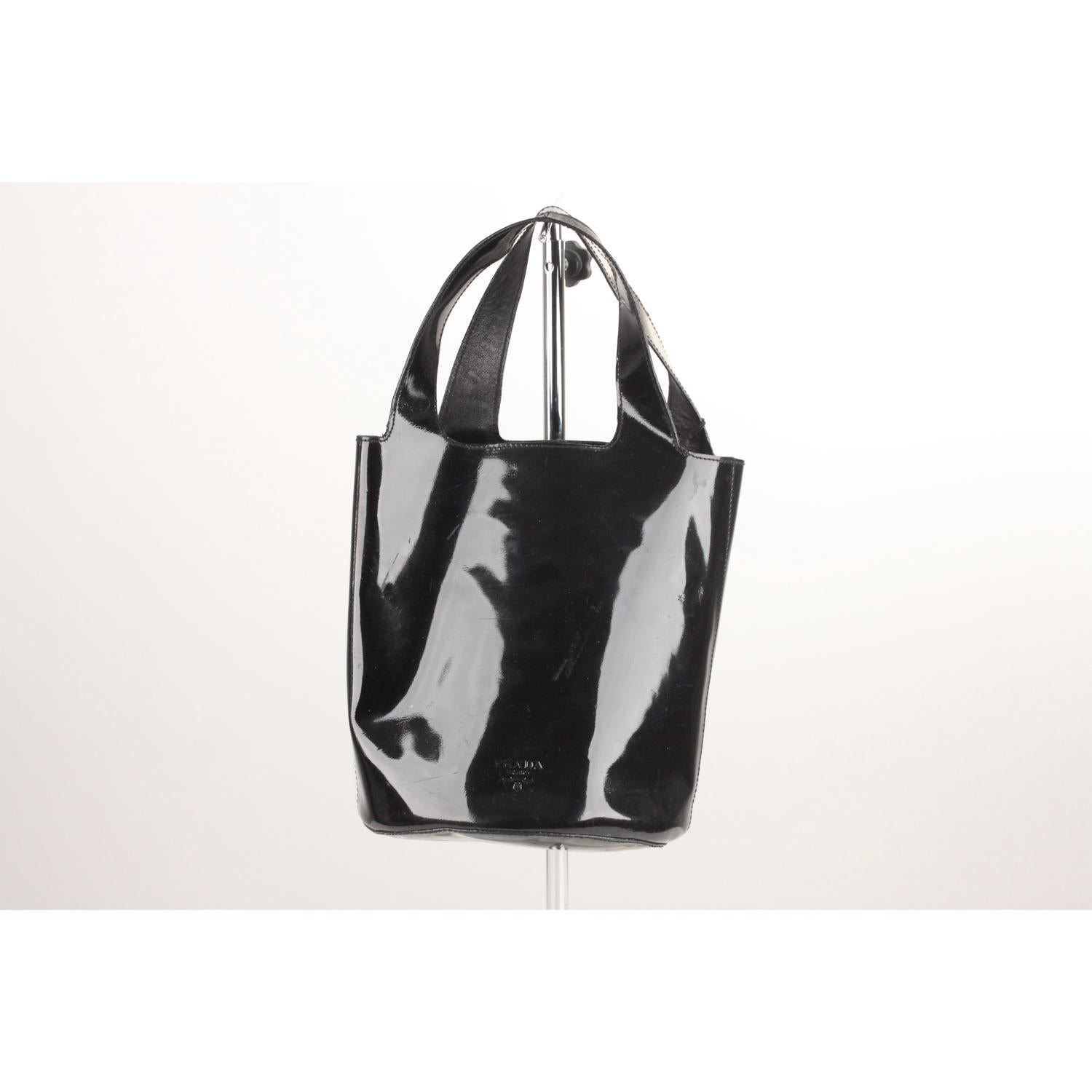 - PRADA Black patent leather bucket bag 
- 'PRADA Milano' engraved on leather tron the front
- Open top
- Black fabric lining 
- 1 side zip pocket
- Double top handles