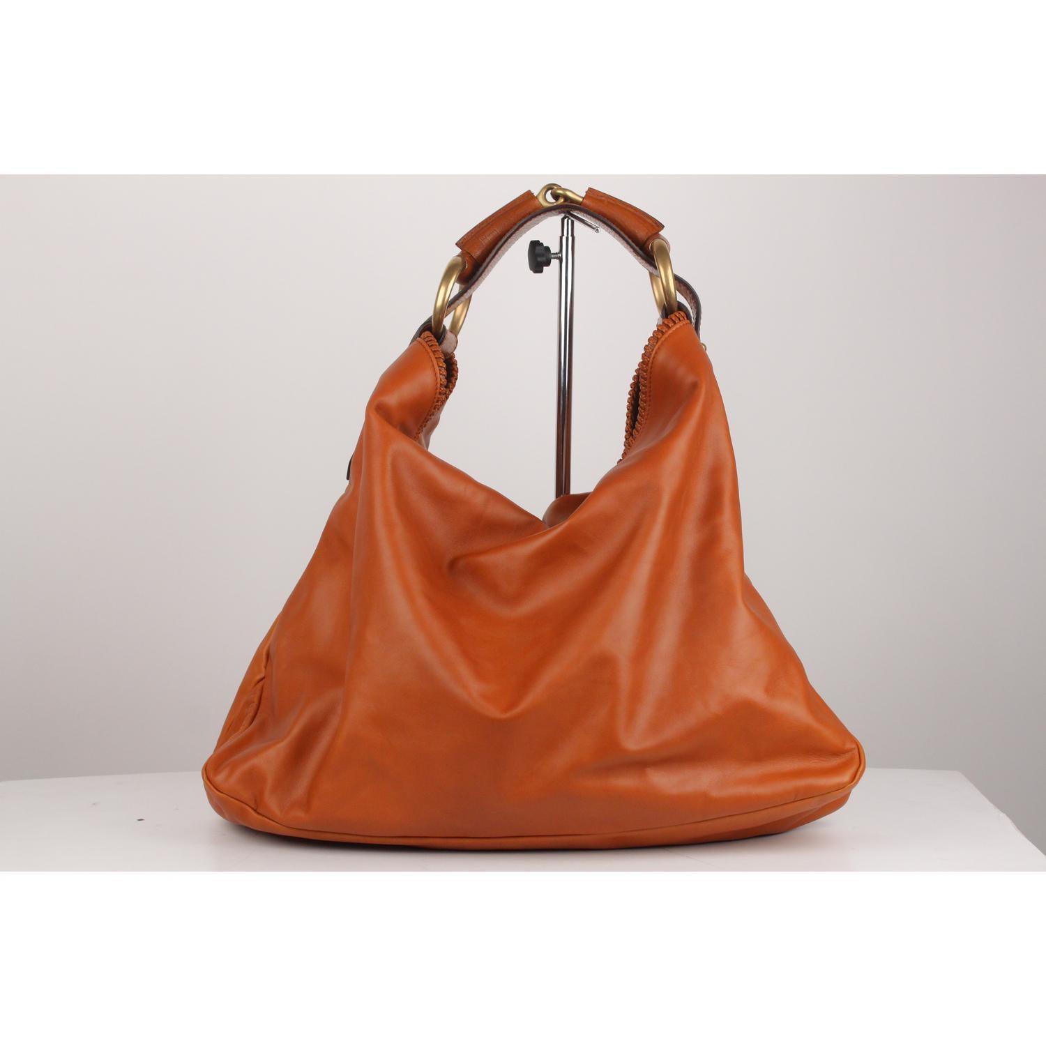 Gucci large hobo shoulder bag crafted in Tan leather.  Gold metal horsebit detailing on the shoulder strap . Open top with stitching detailing on the border. Inside, brown suede lining. and 1 side zip pocket. 'GUCCI - made in italy' tag inside (with