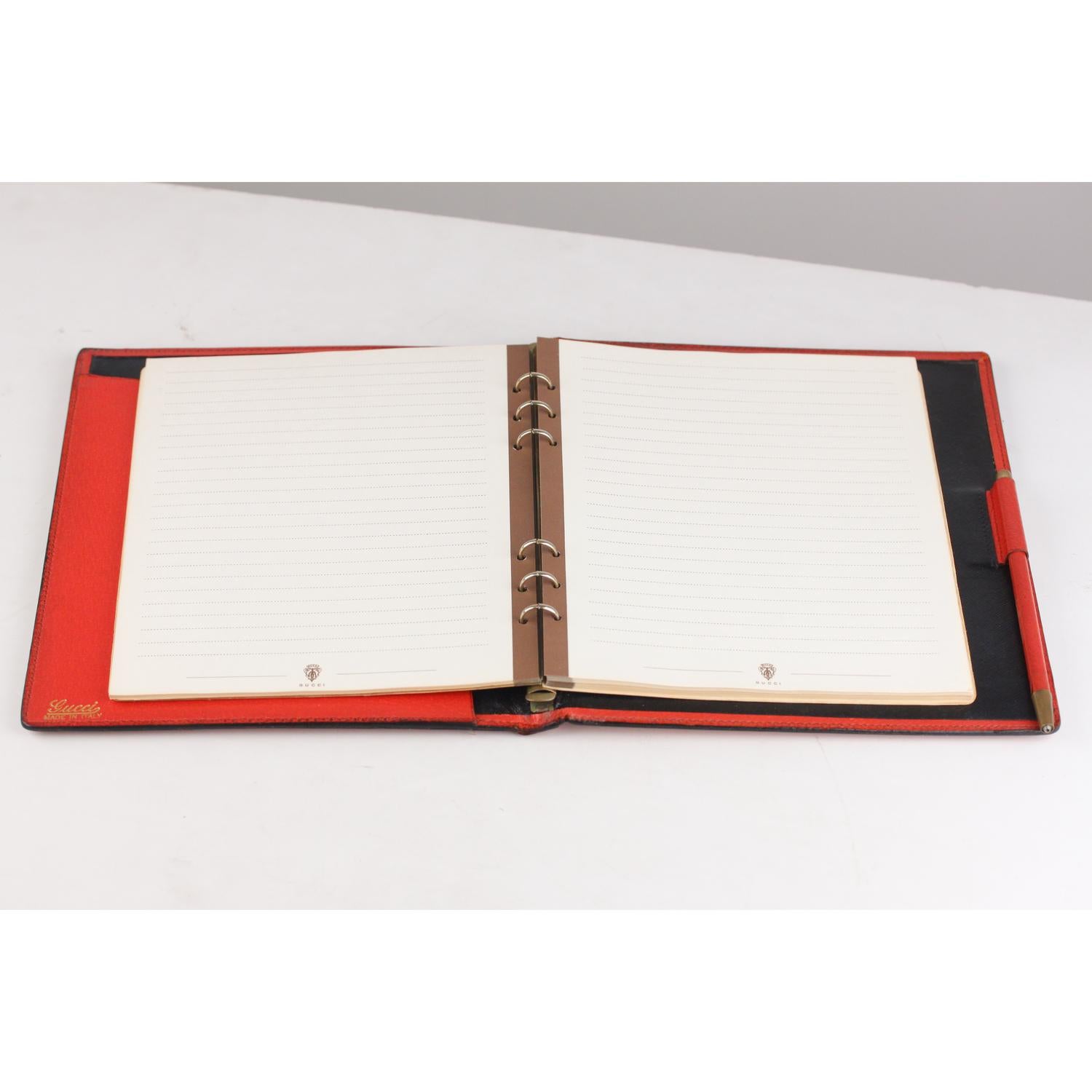 Elegant vintage agenda cover by GUCCI crafted red leather. Black leather interior. It features a six ring binder with original GUCCi notes sheets. Mechanical pencil included. 1 side open slot. 'GUCCI - Made in Italy' embossed inside.