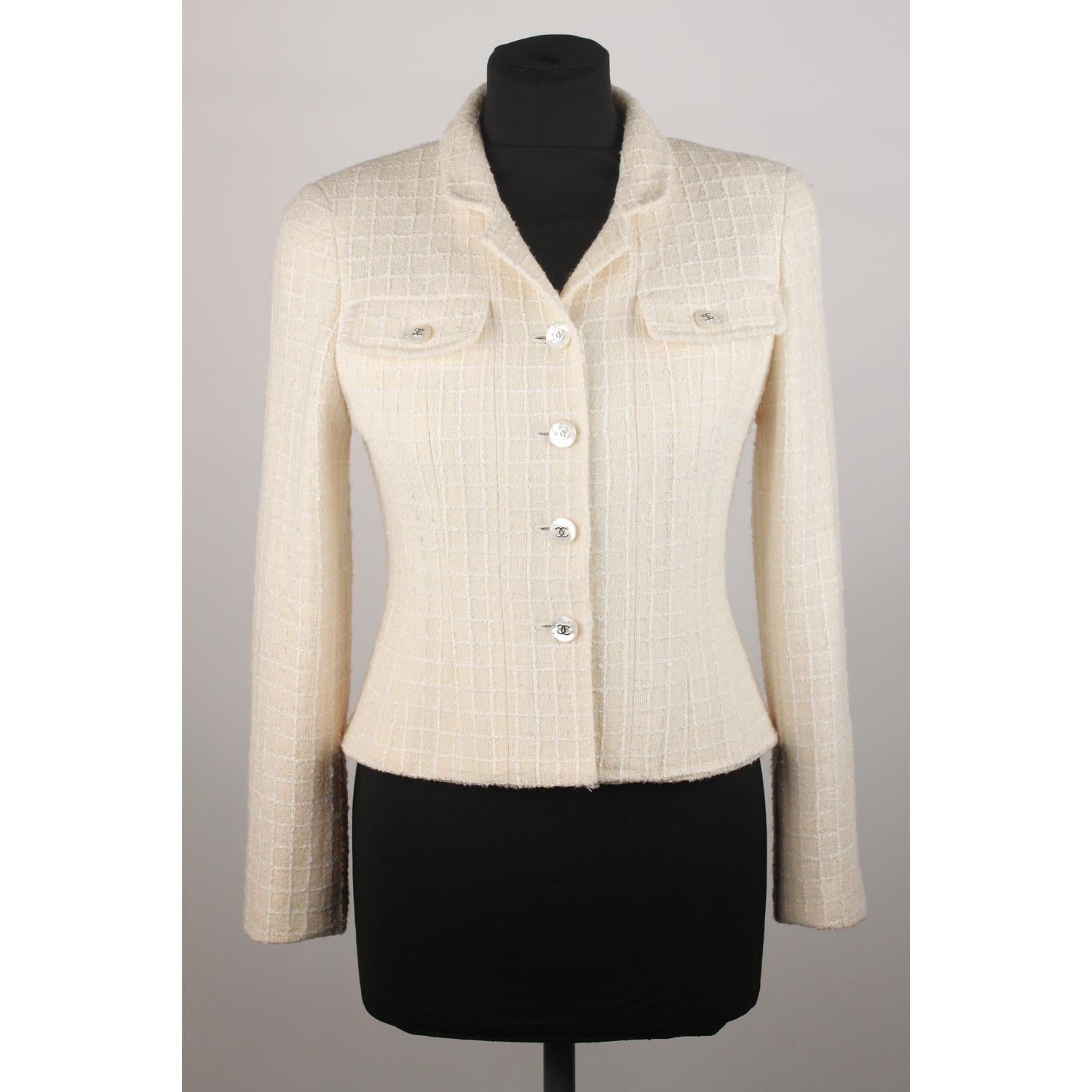 Chanel 97P  bouclé blazer in ivory color. It features 4 -button closures and buttoned cuffs with CC - Chanel logo buttons. Fully lined. Silver metal  chain detail on the hem (internally).  Made in France. Composition 56% wool, 35% nylon, 9% spandex.