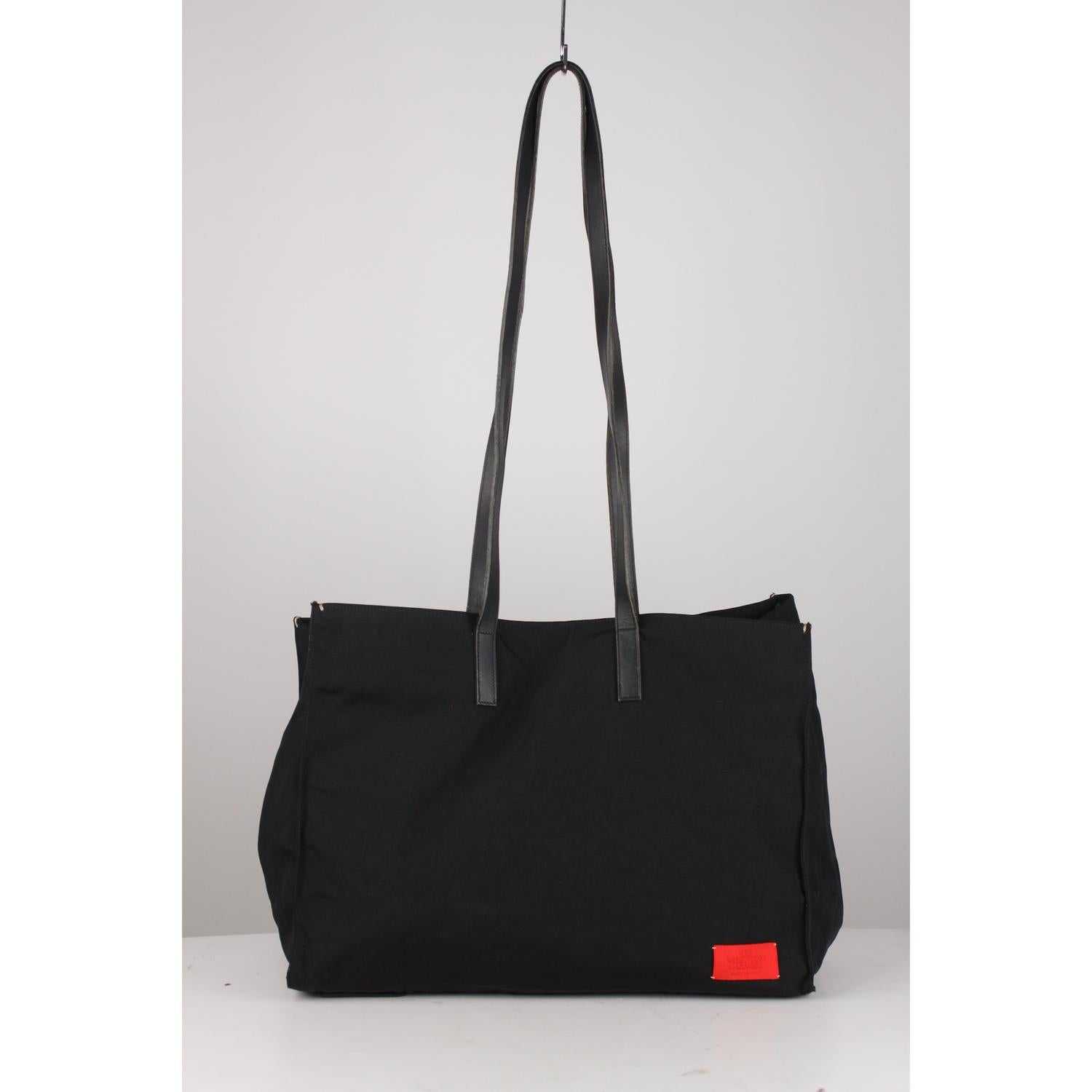 Large Valentino Garavani black canvas tote with long leather shoulder straps. Magnetic button closure on top. Fabric lining. 1 side zip pocket inside. 'Valentino Garavani - Made in Italy' red tag on the front and inside.