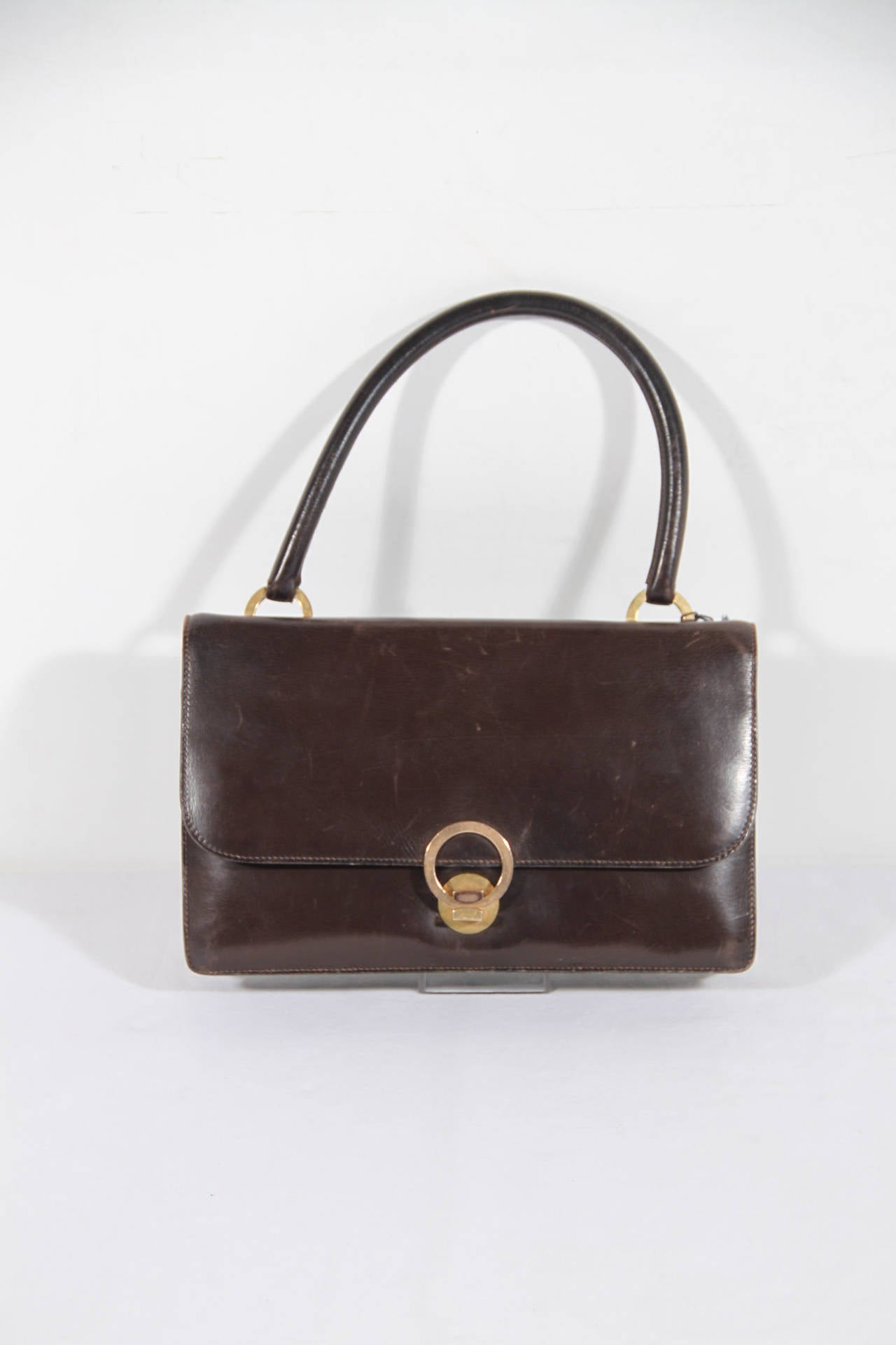 - Model: RING BAG

- Period/Era: Circa 1960

- Made from genuine brown leather

- Gold metal hardware

- Flap with clasp closure

- 1 open pocket on the front (under the flap)

- 2 main sections with 2 side flap pocket, 1 compartment