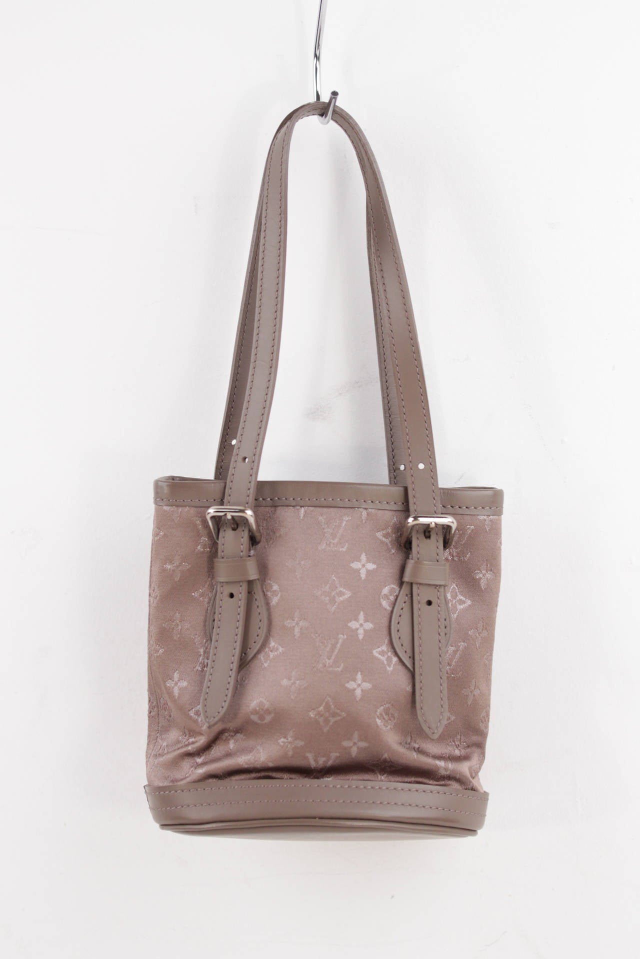 - Model : Louis Vuitton 'Monogram Satin' Mini Bucklet - Monogram Satin canvas in taupe color - Genuine leather details - Silver metal hardware - Open top - Brown Satin interior - This Micro Mini Bucket bag is the shrunken down version of the iconic