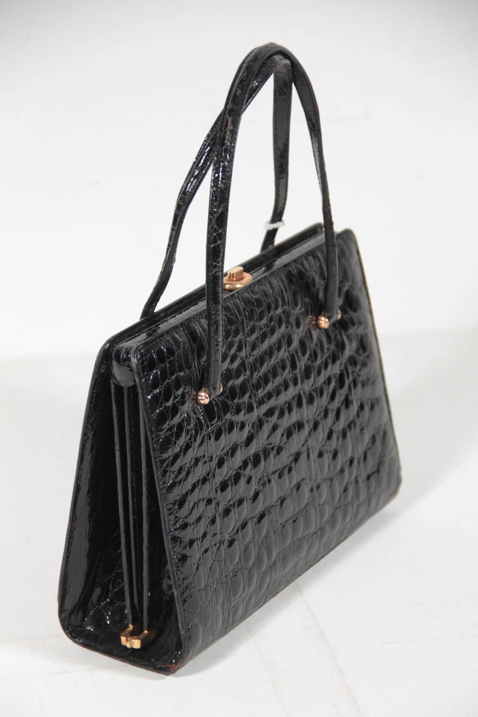 - Period/Era: Circa 1960s

- Black Crocoidle skin

- Double top handles

- Upper push closure

- 4 small protectives bottome feet

- 2 main sections inside with1 middle zip pocket

- 1 side zip pocket, 1 side open pocket and 1 lipstick