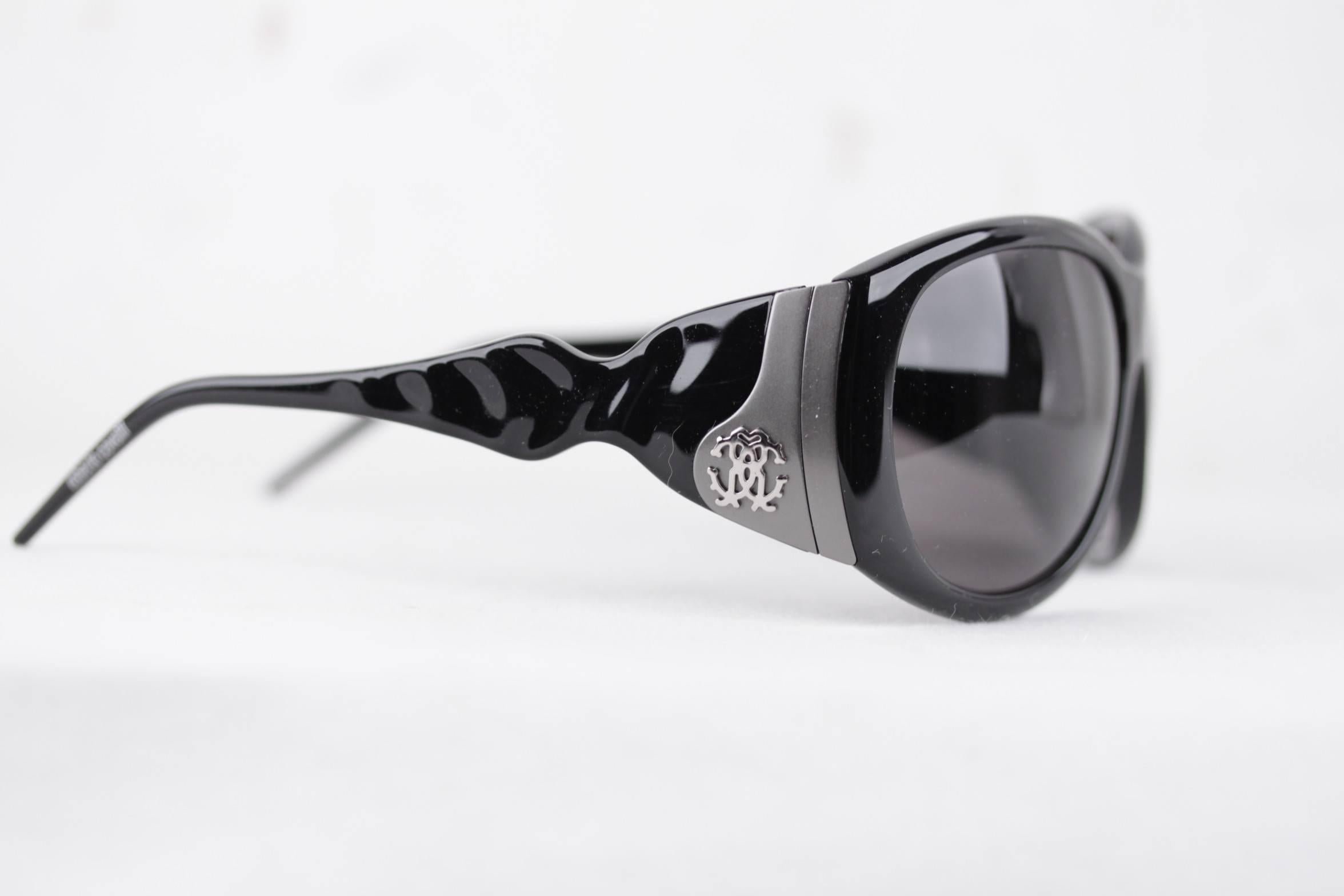 
- ROBERTO CAVALLI - Made in Italy

- Black oversized wrap frame, with silver metal CAVALLI logo on both sides, on a gray finish - Smoke blue lens

- Model refs: CARITE 288S - B5 - 59/15 -  130

- signed CAVALLI 100% UV protection original