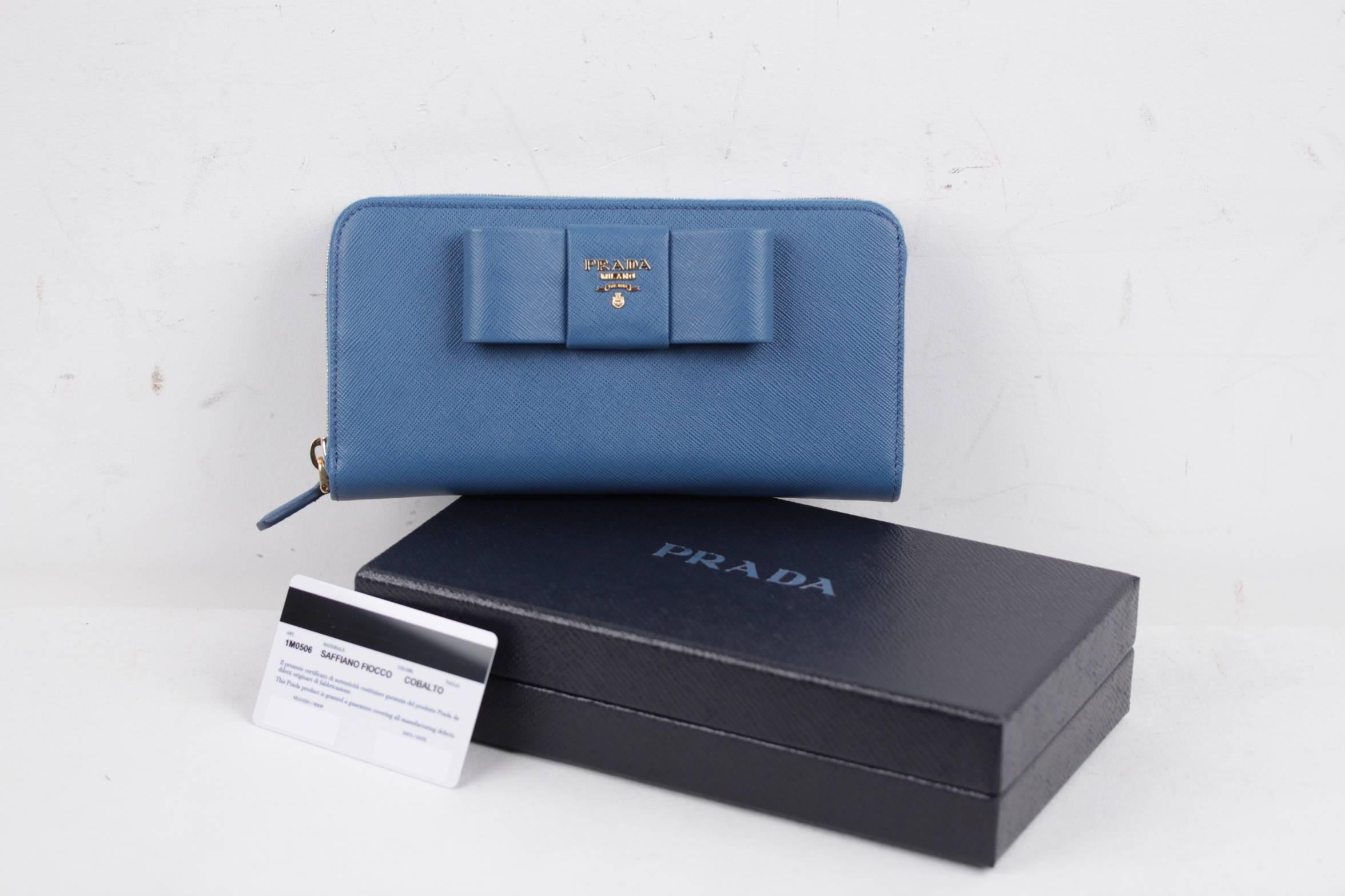  - Saffiano leather wallet with leather bow of the front
- Color. Light Blue (Official PRADA color is COBALTO)
- Art. 1M0506 - SAFFIANO FIOCCO
- Gold-plated hardware
- Metal lettering logo
- Zipper closure
- 12 credit card slots
- 6 inside