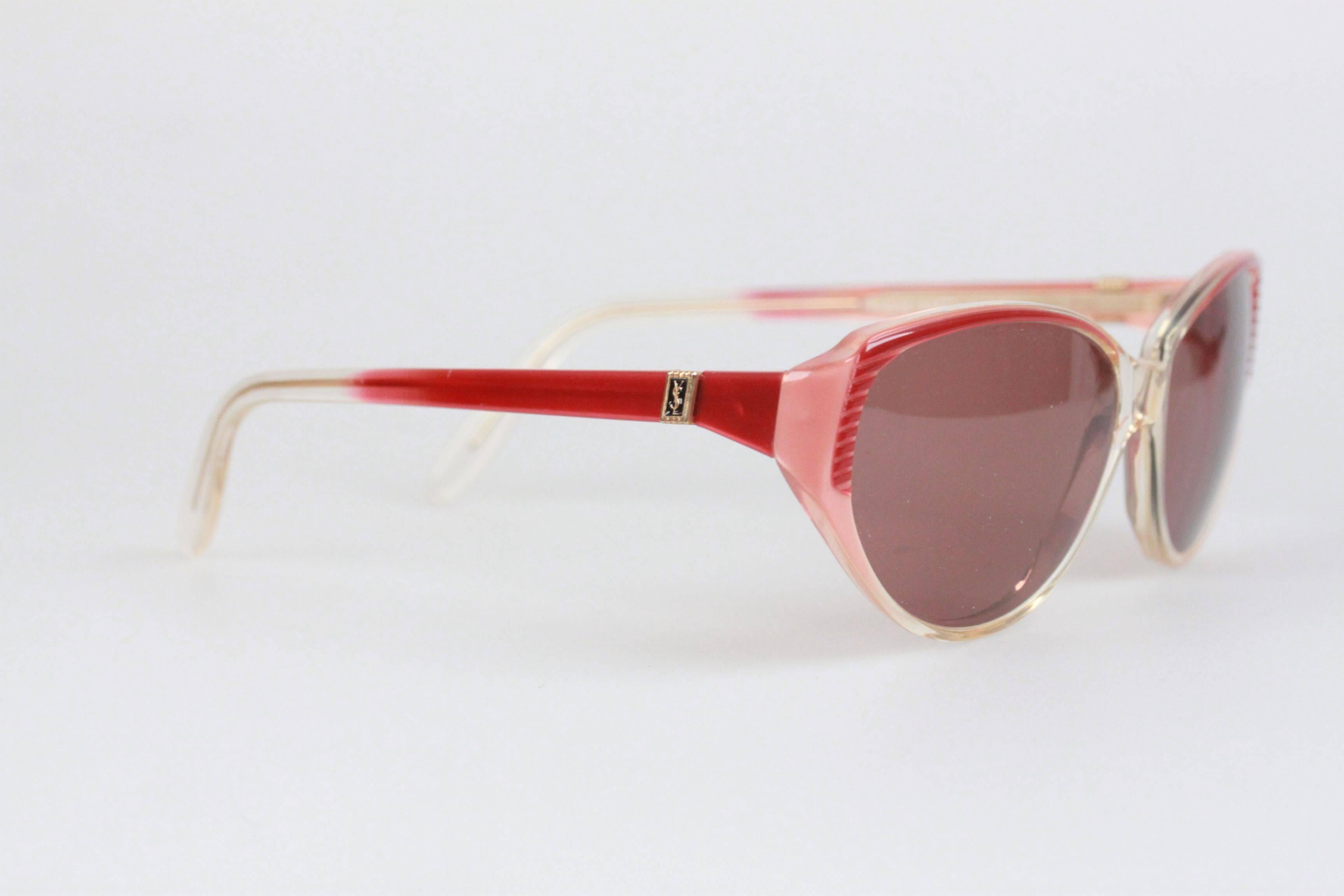 - Mod. ISMENE
- Period/Era: 1980s
- Red-Pink/Clear plastic frame
- Yves Saint Laurent logo on temples
- 100% UV protection gray lenses
- Made in France

Measurements:
- TEMPLE LENGTH: 135 mm
- TEMPLE TO TEMPLE - MAX WIDTH: 130 mm
- EYE / LENS WIDTH: