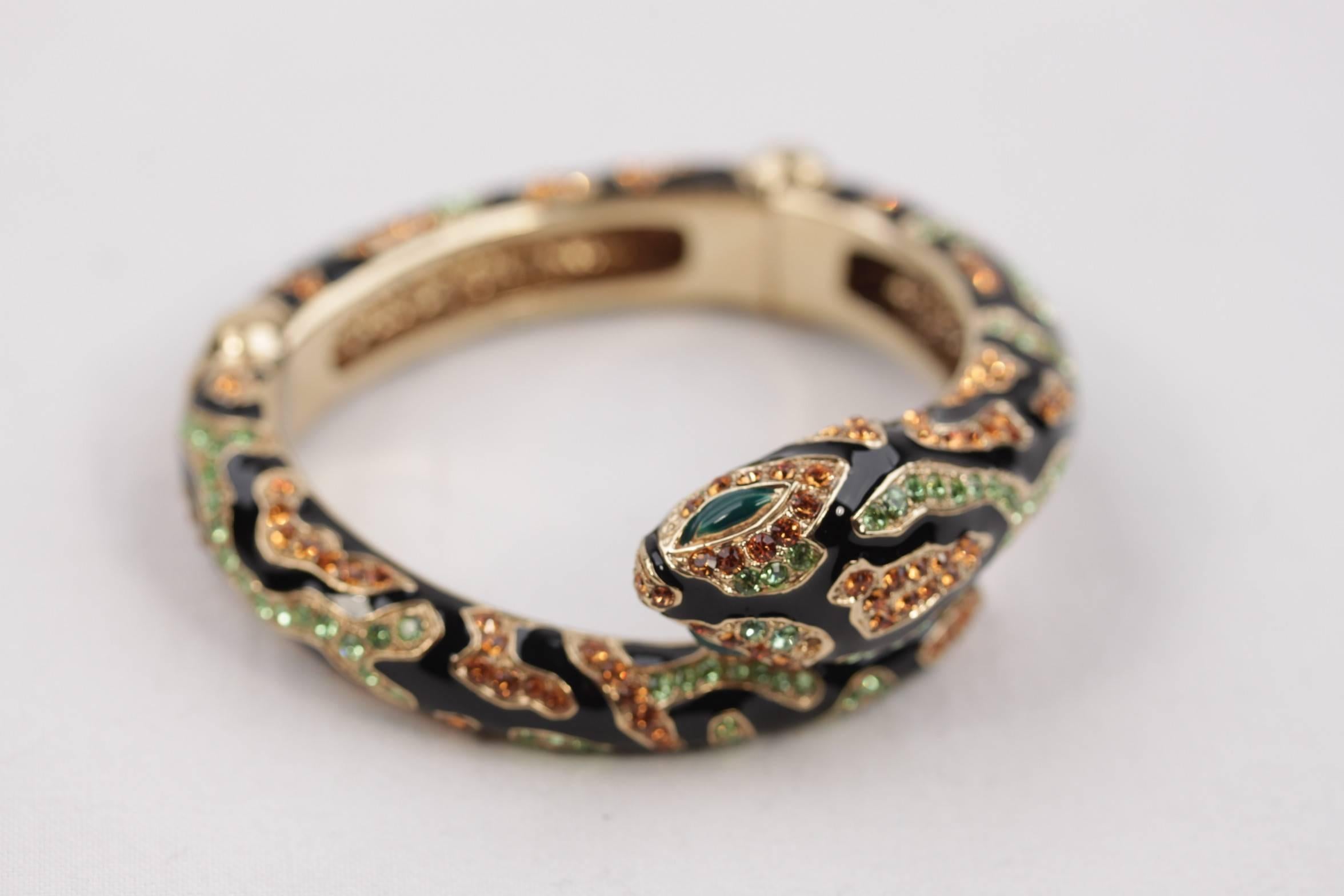 - Gold-tone brass 'Snake' bracelet with black enamel by ROBERTO CAVALLI

- With Orange & Green crystal embellishment.

- Green enameled eyes eyes

- 2 hinges to slip on

- Approx. inner diameter: 2 1/4 inches - 5,7 cm

- Marked 'ROBERTO