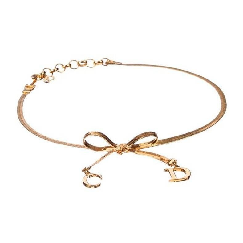 18 kt gold plated chain necklace by Dior with a bow and CD charms. From John Galliano Era.

Necklace measures 12” to 14”, adjustable, with approximately 1 ½” drop.
Chain is 3 mms wide.