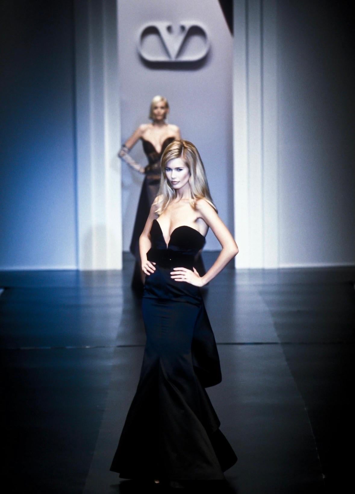 Presenting a fabulous black satin Valentino Garavani strapless gown. From the Fall/Winter 1995 collection, this floor-length gown debuted on the season's runway, modeled by Claudia Schafer. Constructed almost entirely of lustrous black silk satin,