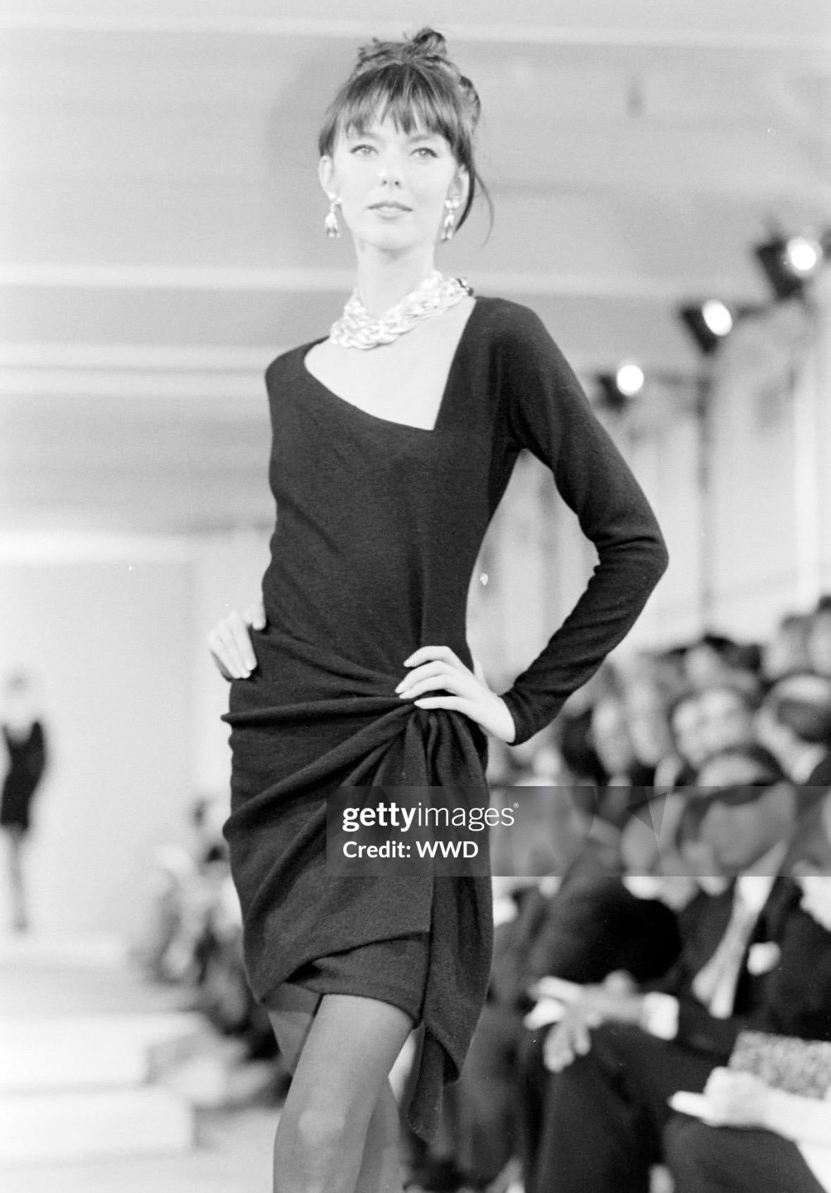 Presenting a chic black Donna Karan dress. From her Fall/Winter 1990 collection, this fabulous black dress debuted on the season’s runway on Brynja Sverrisdóttir. An asymmetric neckline, long sleeves, and a draped accent at the front create a chic