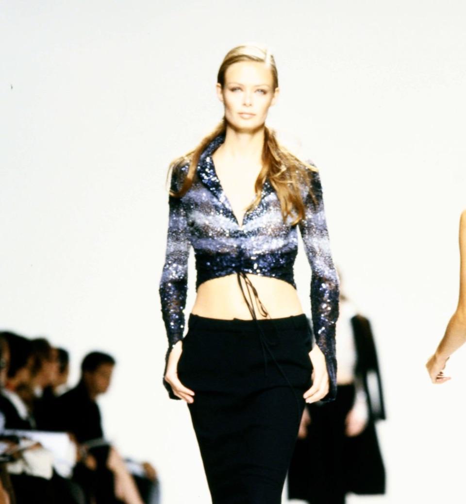 From Randolph Duke’s Spring/Summer 2000 collection, this cropped long sleeve top is crafted from sheer tie-dye mesh densely covered in shimmering sequins. It features a plunging neckline with an adjustable drawstring ruched front, elongated cuffs,