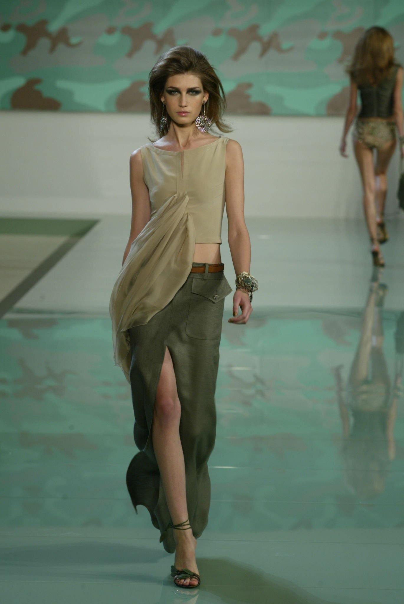 Dalla collezione primavera/estate 2003 di Valentino Garavani, questa maxi gonna nera in seta grezza presenta tasche oversize in stile cargo ornate da bottoni a stella dorati. Il tessuto è caratterizzato da una sottile consistenza a coste, tagliato