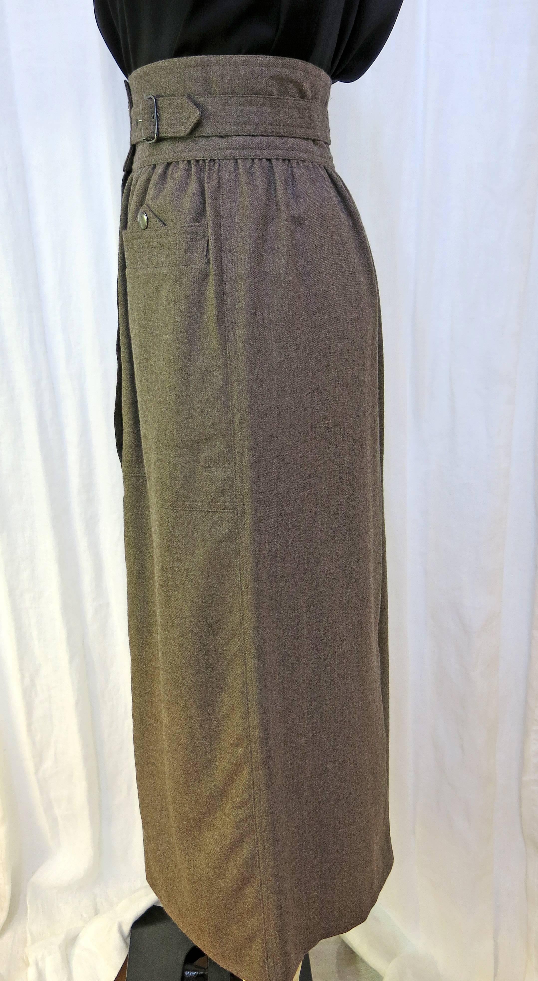 High waisted wool full length skirt. Belted at the waist with two button closure pockets at the front and one at the back of the garment. Two button closure at the waist of the skirt. Conservative slit at the back for easy movement. Unlined. Would