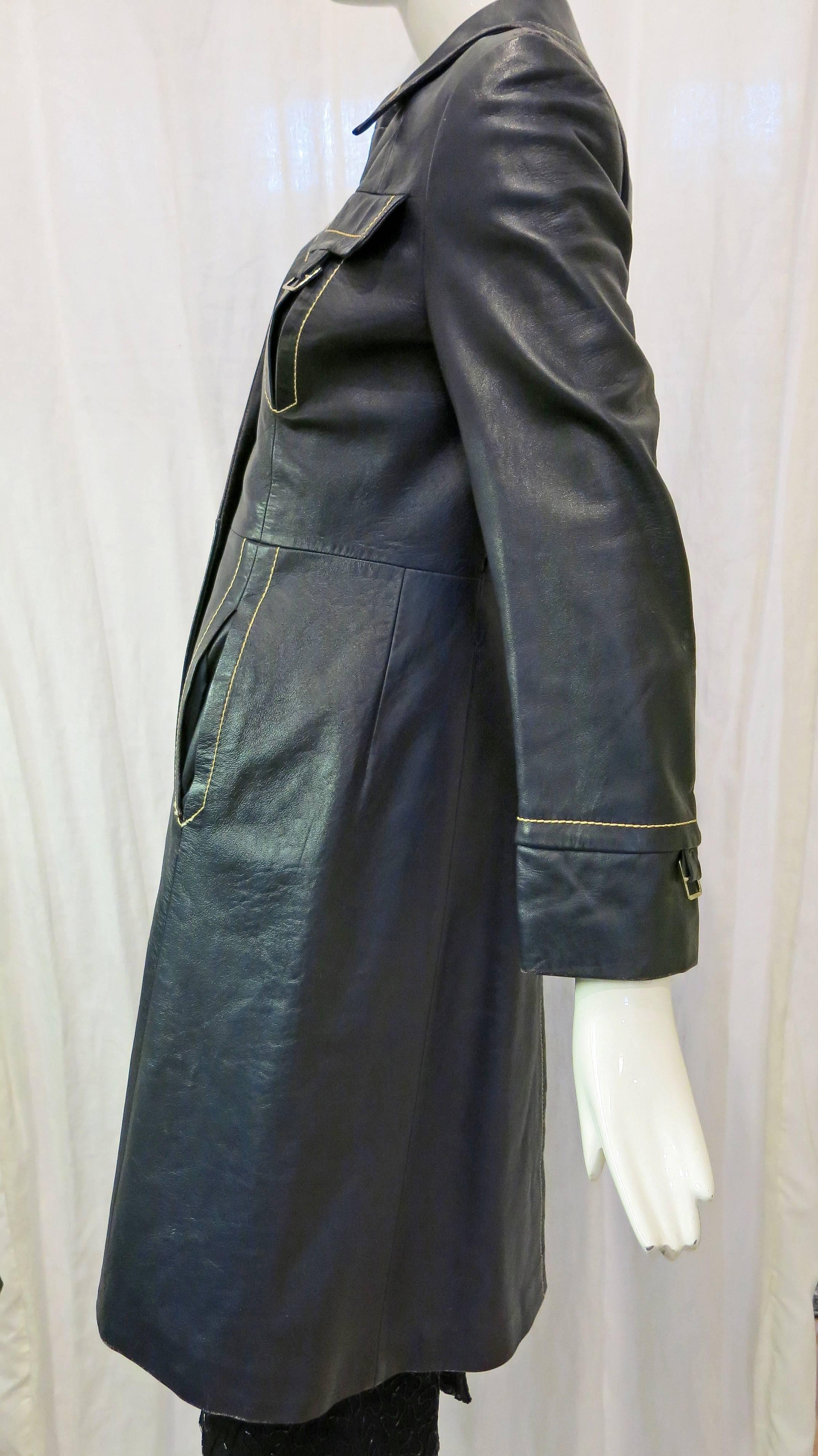 Navy blue leather trench with white contrast stitching. Missing belt. Five metal buttons down the front. Some light wear to the leather throughout. Inner lining in great condition. 14.5