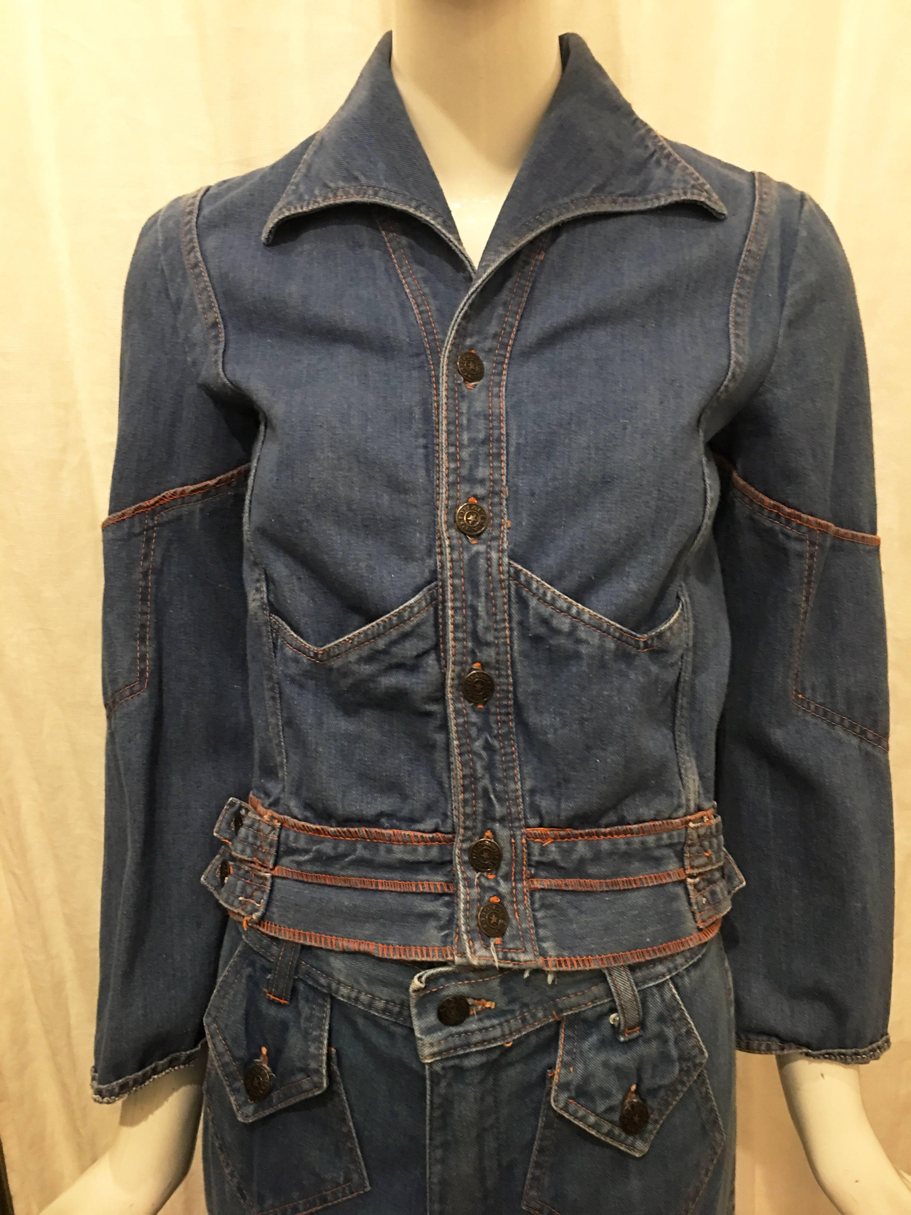 Denim jacket and jean two piece pant suit with embroidered tree and sun print on the top back and back waistline of the top and pants. Button with zip fly closure on jeans. Two button closure pentagon shaped pockets. No pockets at back of jeans. 5