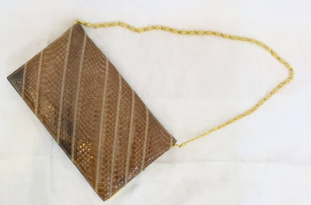 This exotic snakeskin flap purse with zig-zag stitching features a gold plated strap with gold plated tips on the front flap. The interior is lined with brown leather and black fabric pockets and is labeled 