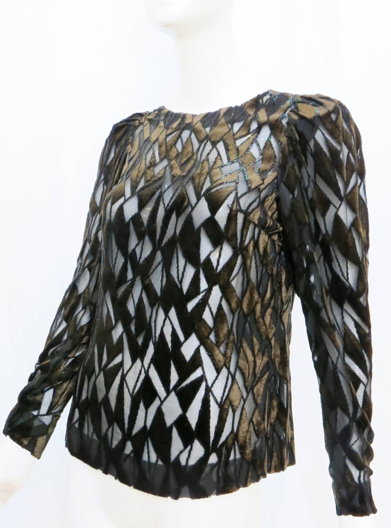 Perhaps from his start as a milliner, designer Adolfo Sardina understands attention to detail. This 1980s sheer blouse with a stained glass pattern of black and brown velvet offers refinement with self-assured sensuality. This tops zips up the back