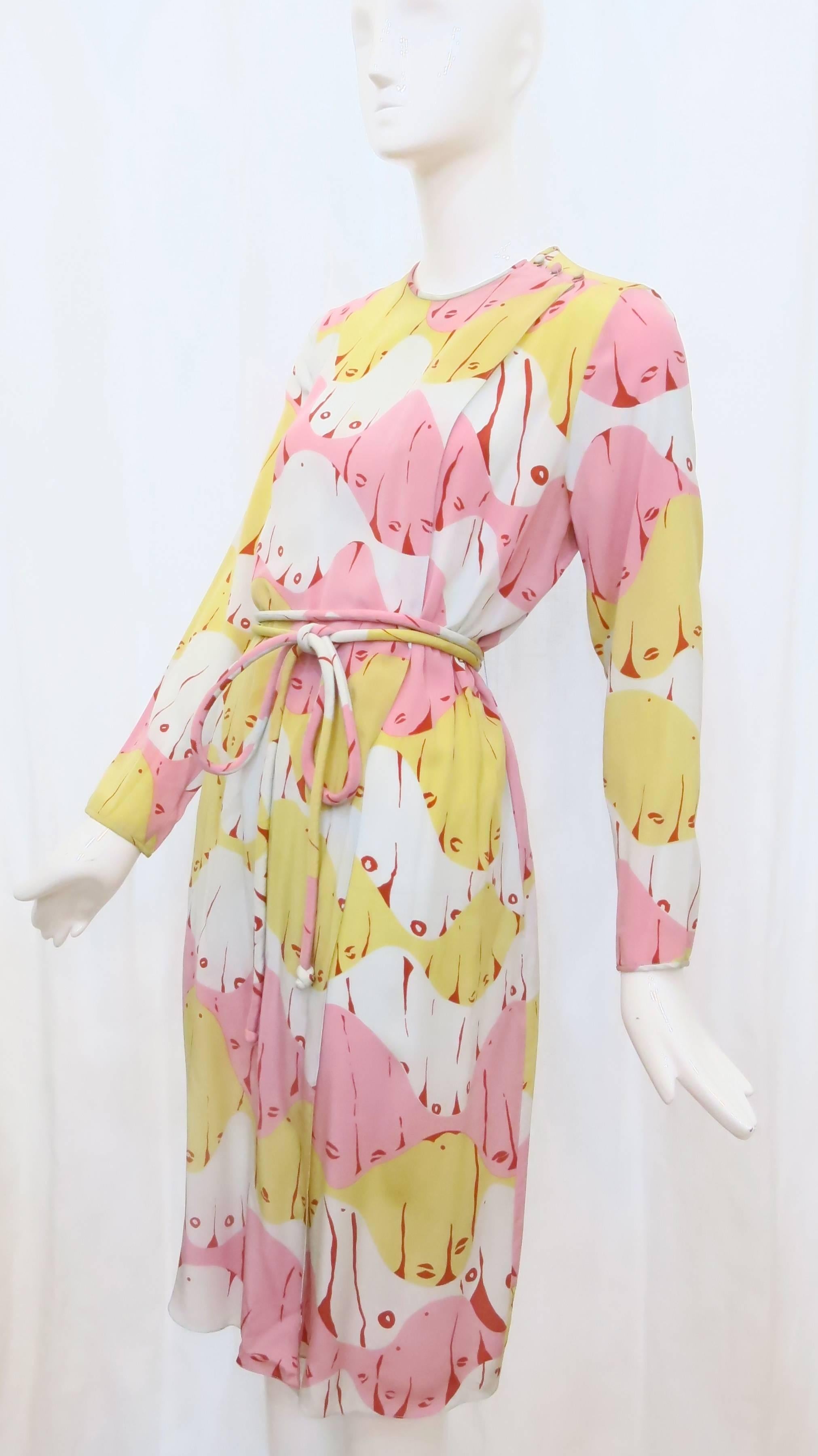 Bright and sensual, this silk wrap dress by Mary McFadden features an abstract print that looks like a multitude of faces. A long, tubular matching belt adds to the softness and fluidity of this dress. The dress opens up like a robe and snaps inside