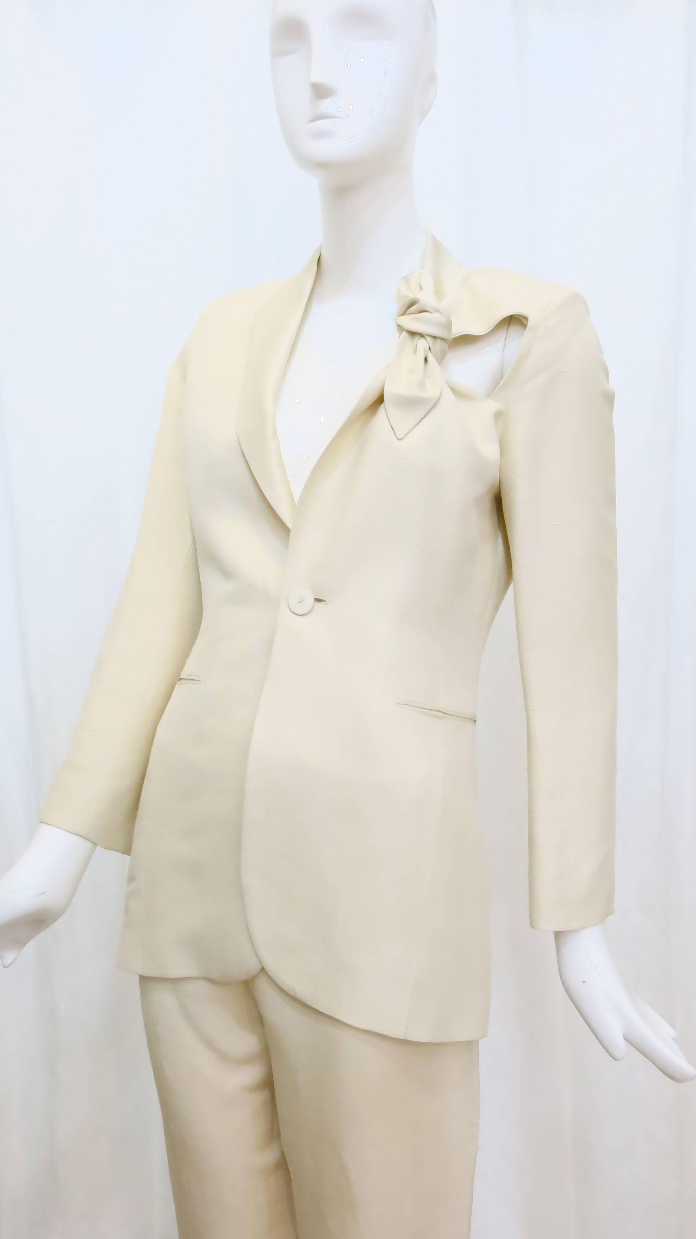 A master of taking archetypes in fashion and adding his own subversive twist, this cream suit by Jean Paul Gaultier commands attention with padded shoulders and an eye-catching cut-out placed near the top left shoulder. This suit is constructed from