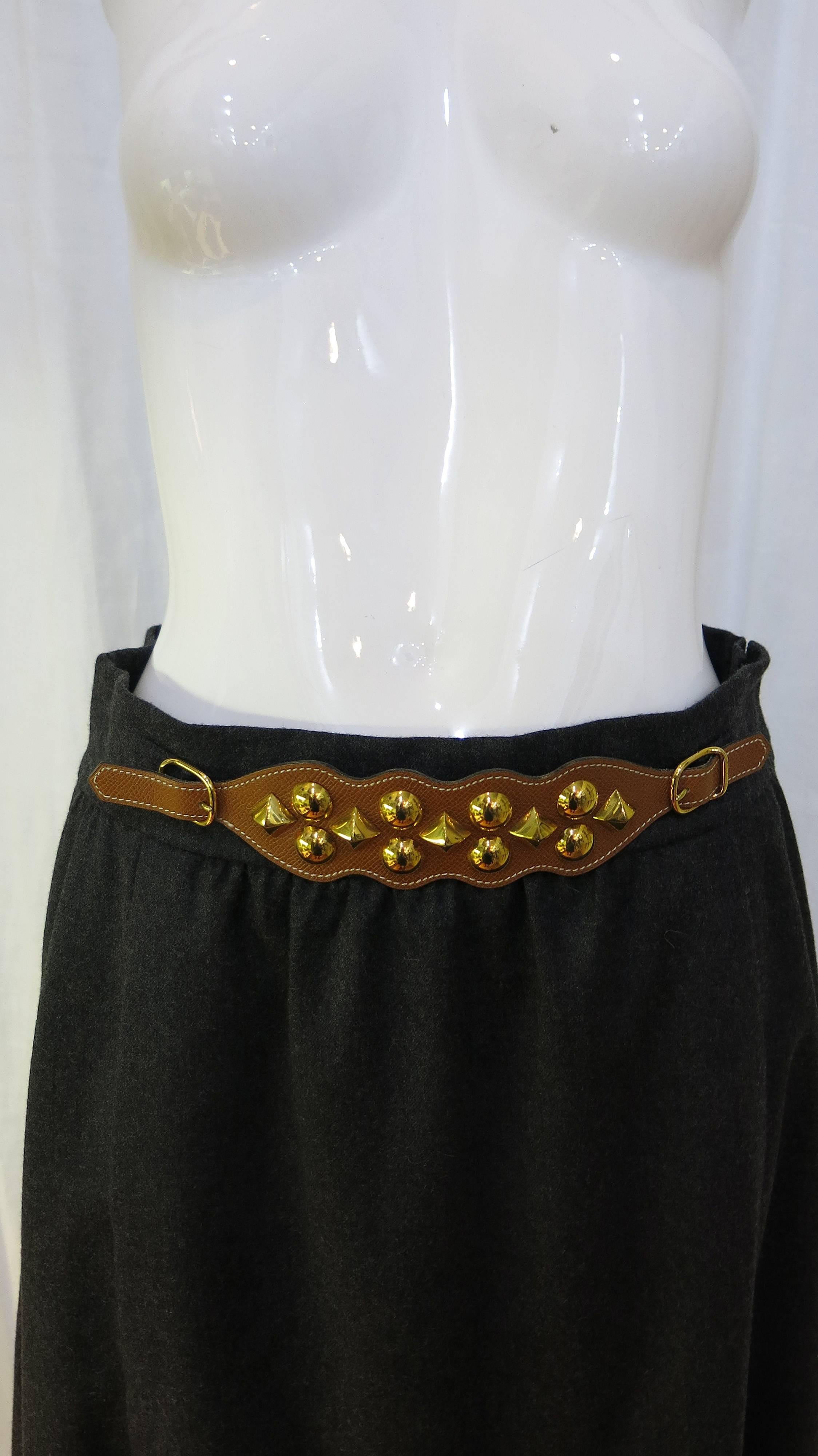 Knee length 90% wool 10% cashmere blend silk-lined A-line skirt with studded leather belt detail. Zips up the side with a double hook and eye closure. Marked as a French size 42 which translates to size 12 in US sizing but fits more like a US size