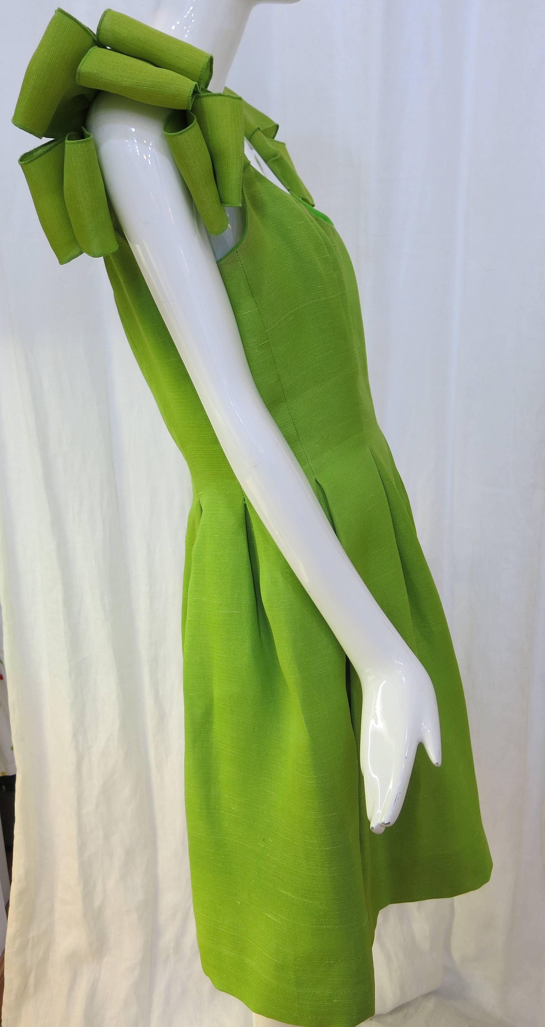 Beautiful, vibrant, lime green pleated sleeveless cocktail dress with looped shoulder detailing. Hits just below the knee in Tea Dress fashion.

Made from raw silk, this eye catching dress would be perfect for a summertime evening night on the
