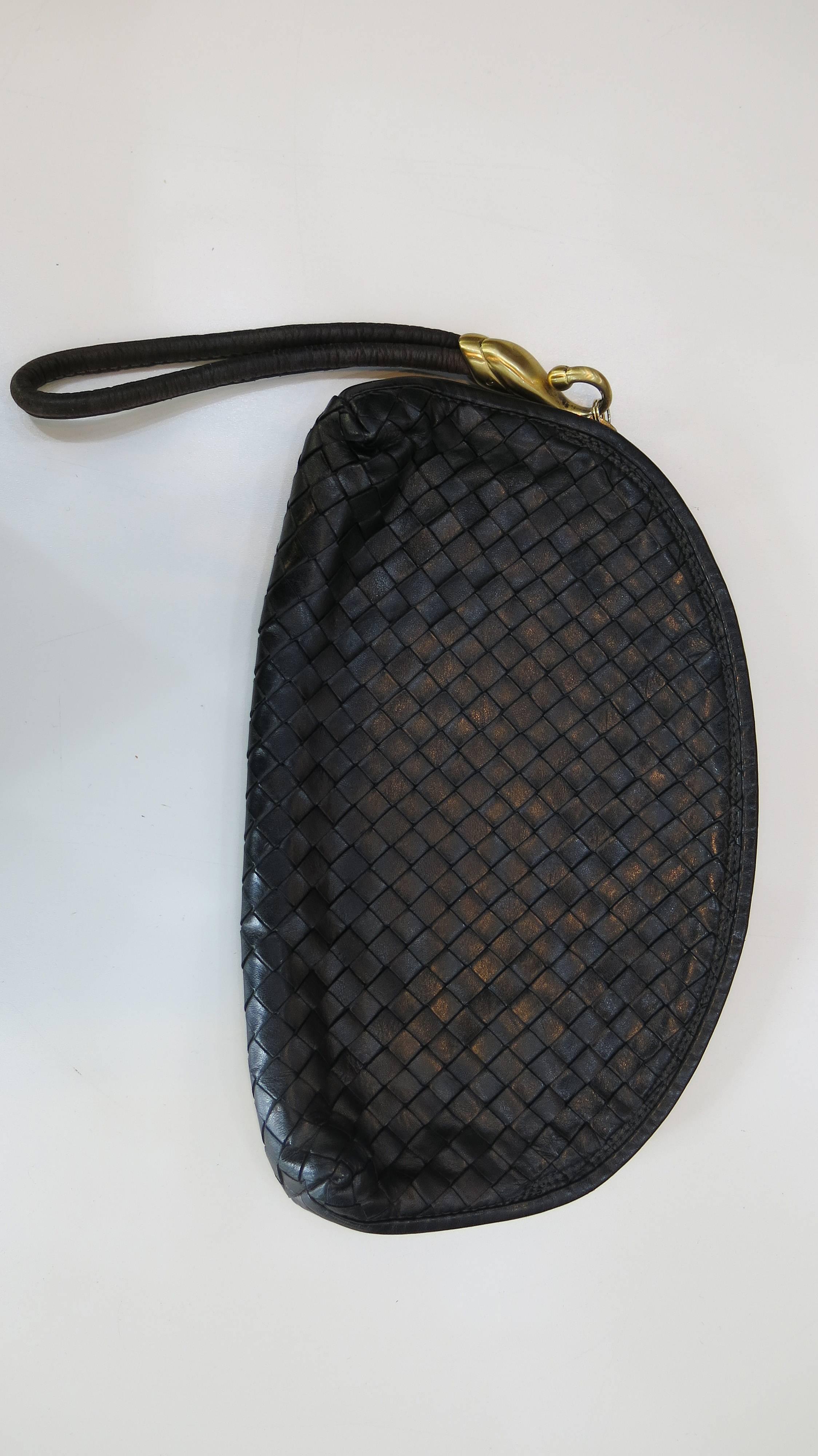 Black woven leather Bottega Veneta clutch. The bag appears virtually unused and features an inner zip pocket and an oversized leather pull as well as brass toned hardware. A classic night/day bag. The perfect size to carry the essentials and a