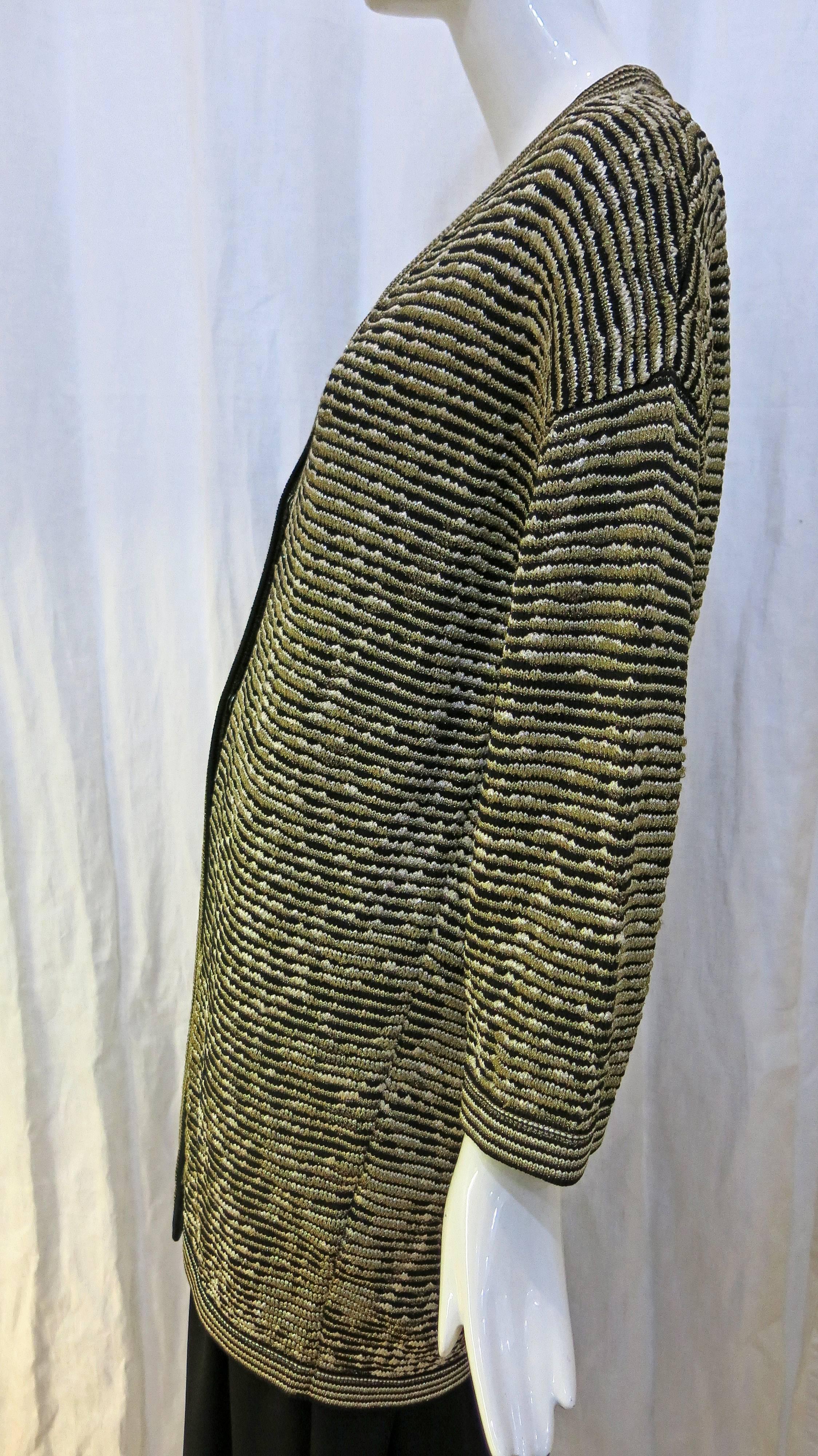 Classic Missoni Chevron stitch in black and metallic gold. Design is an oversized cardigan with two snap buttons. Buttons start almost halfway down the sweater. The sleeves are on the shorter side (hit at wrist length). This would look great over a