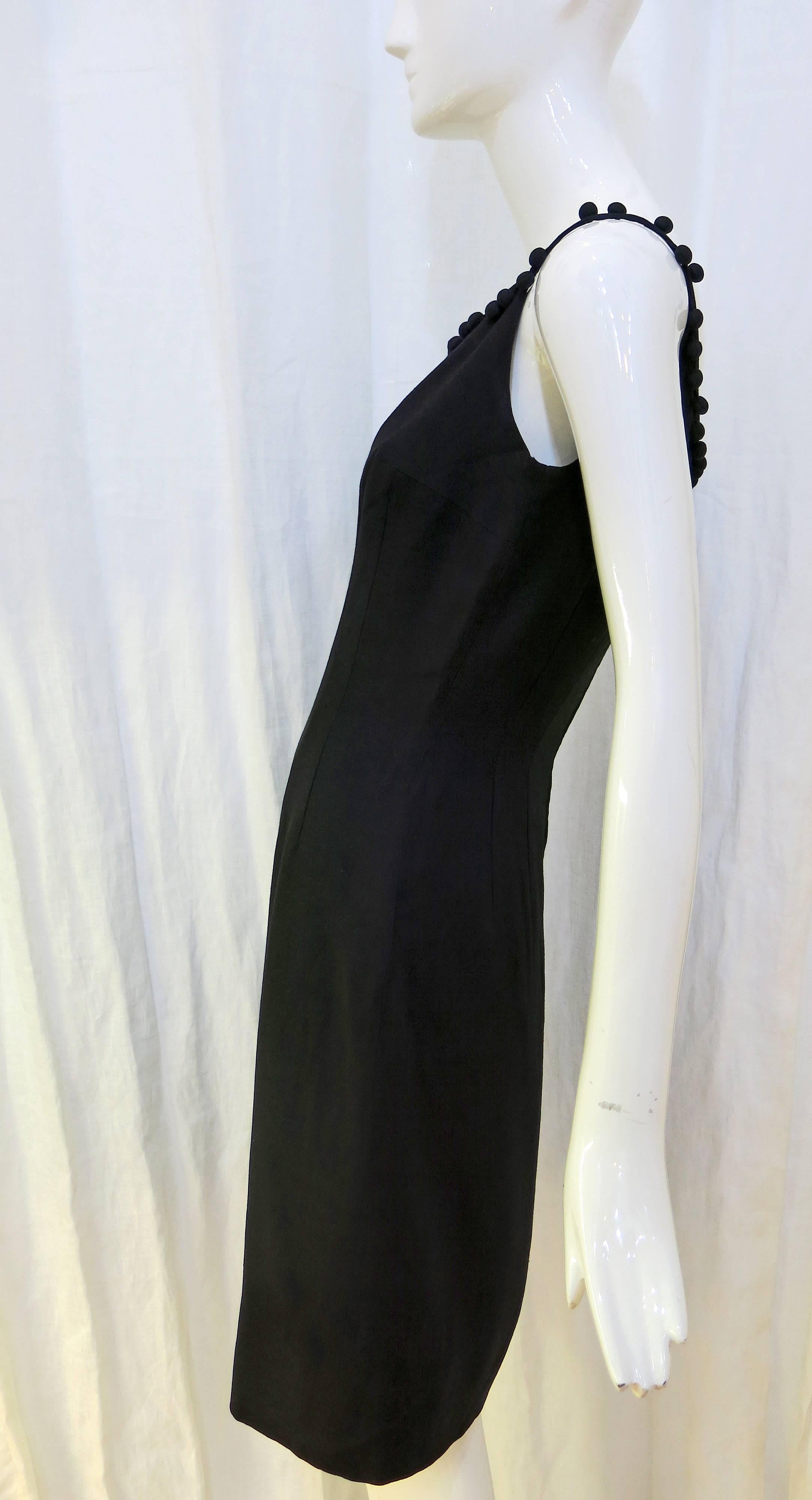 Black simple and classy cocktail dress with pom pom detailing at neckline. Sleeveless, sheath style, zips up the back. Could be worn with a blazer as a workplace ensemble or would make a beautiful summertime dinner dress for a date at a sidewalk