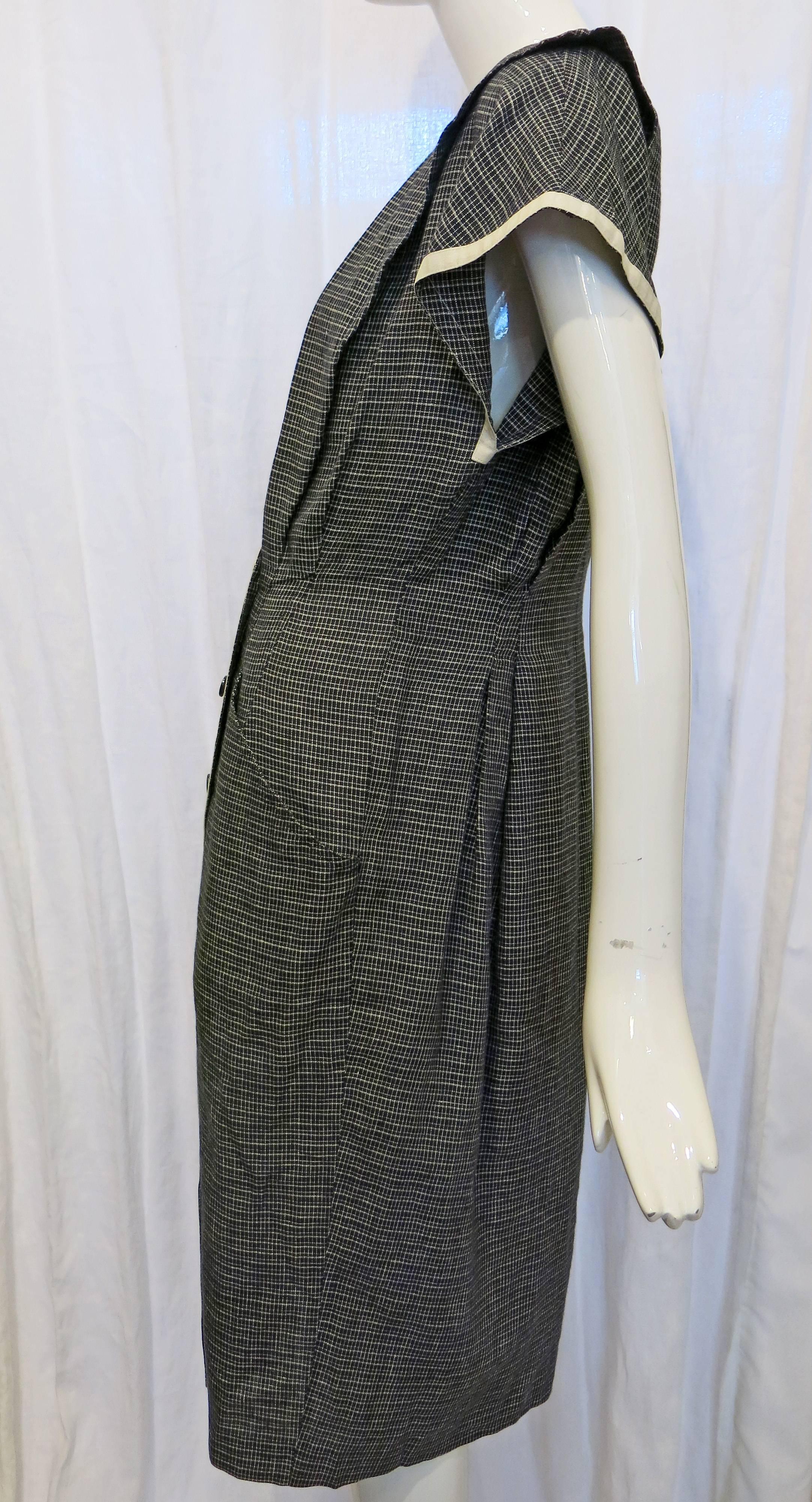 Plaid double breasted Ungaro Solo Donna wrap dress. V cut neckline, pleating at breast. Two front pockets. White trim at neckline and down front of dress as well as at the hem of the sleeves. 

The House of Ungaro opened in 1965 following designer