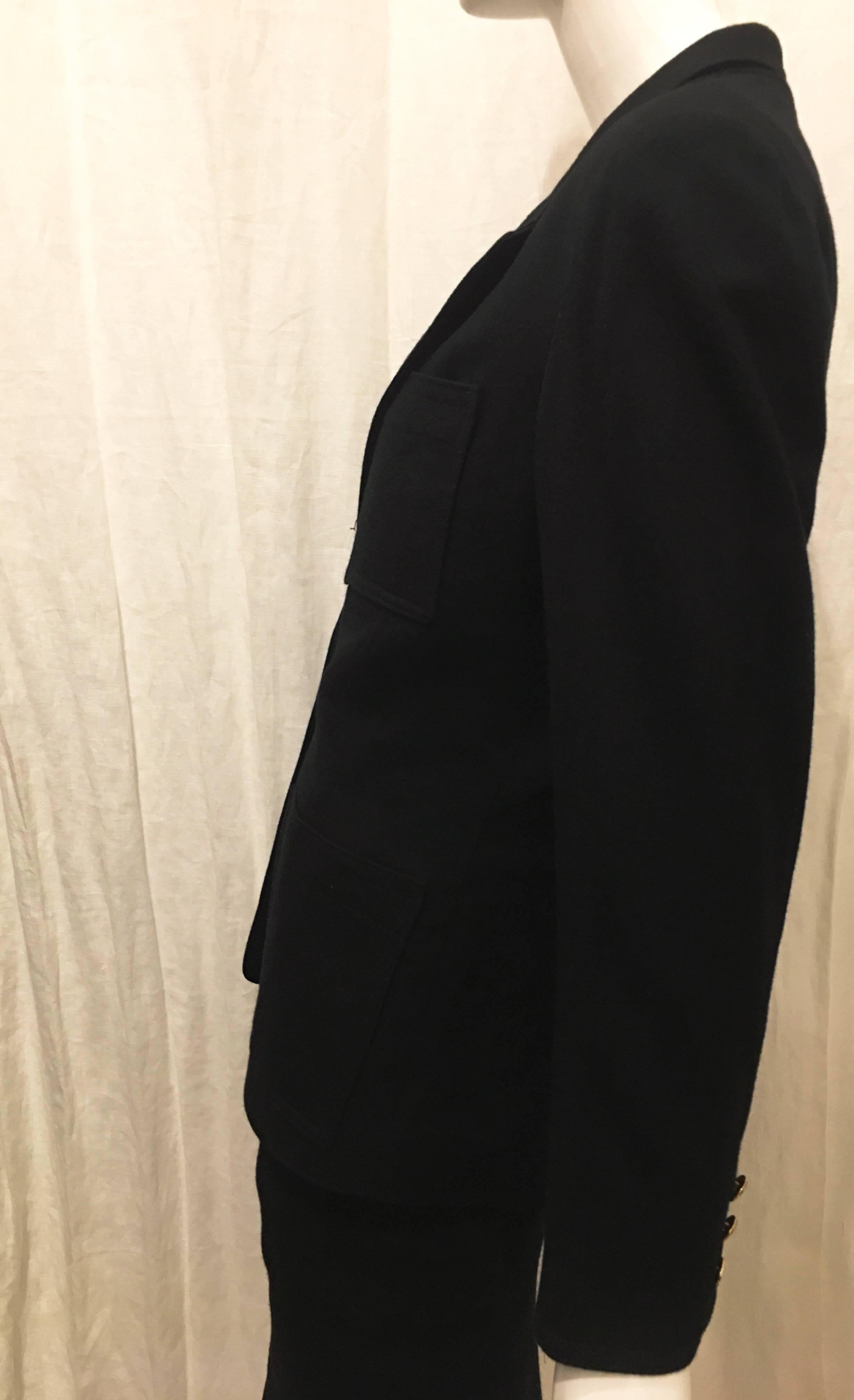 Black wool single button blazer by Givenchy. Closure is single gold button with Givenchy logo. Two pockets at front of jacket close to bottom hem as well as a single pocket at the left breast. Stitching is also black. Simple staple piece that can be