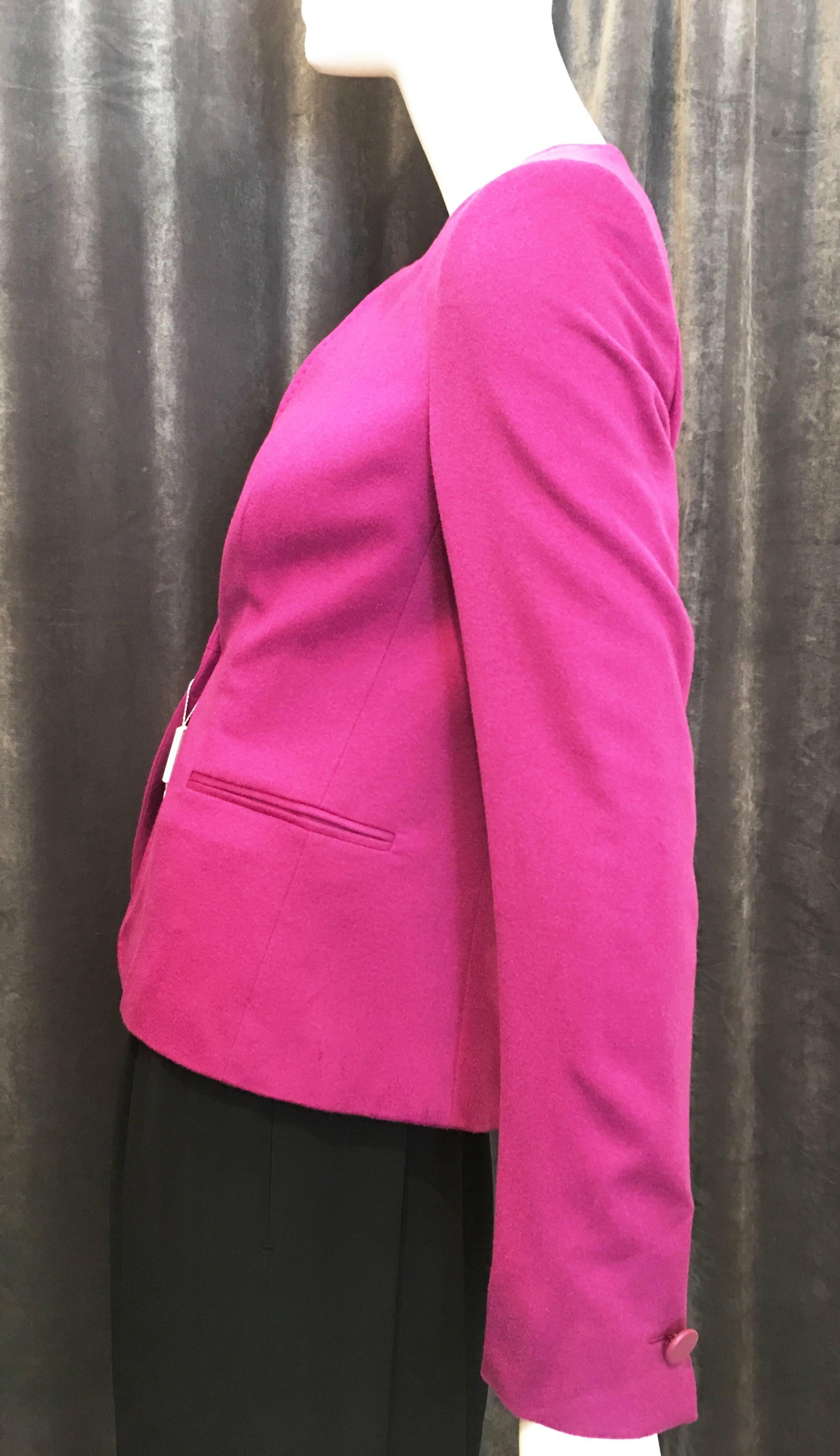Collarless purple blazer with running stitch at collar and down front of jacket. Single leather button closure. Small shoulder pads. Fully lined with logo stamped fabric. Single decorative leather buttons at cuffs. Two front pockets. Classic style