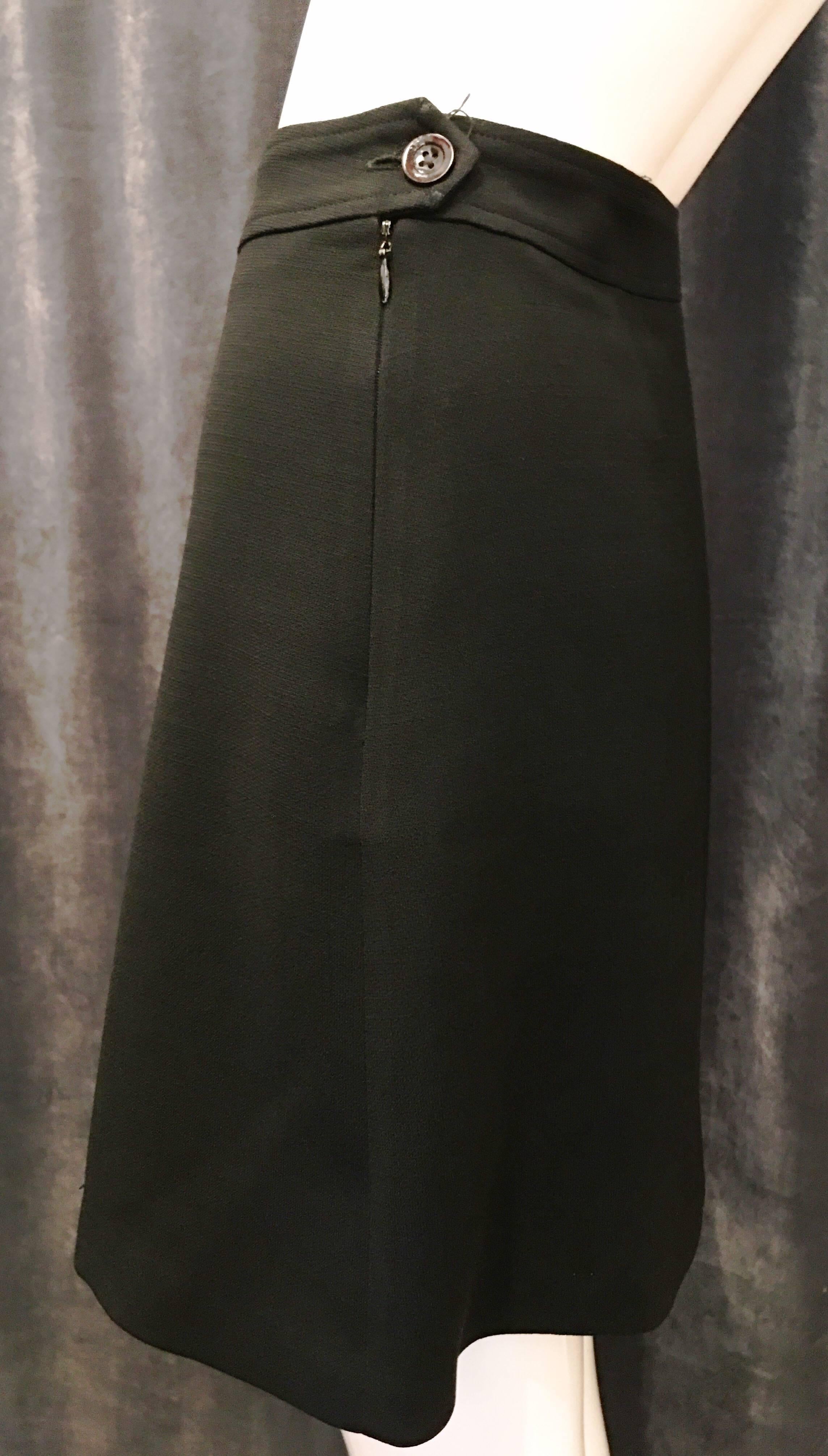 Black pleated mini skirt with single button and zip closure at left side of the garment. Wool. Fully lined. A classic piece that you will be able to pair with anything. Wear with brightly colored tights boots and a cropped top or wool tights and
