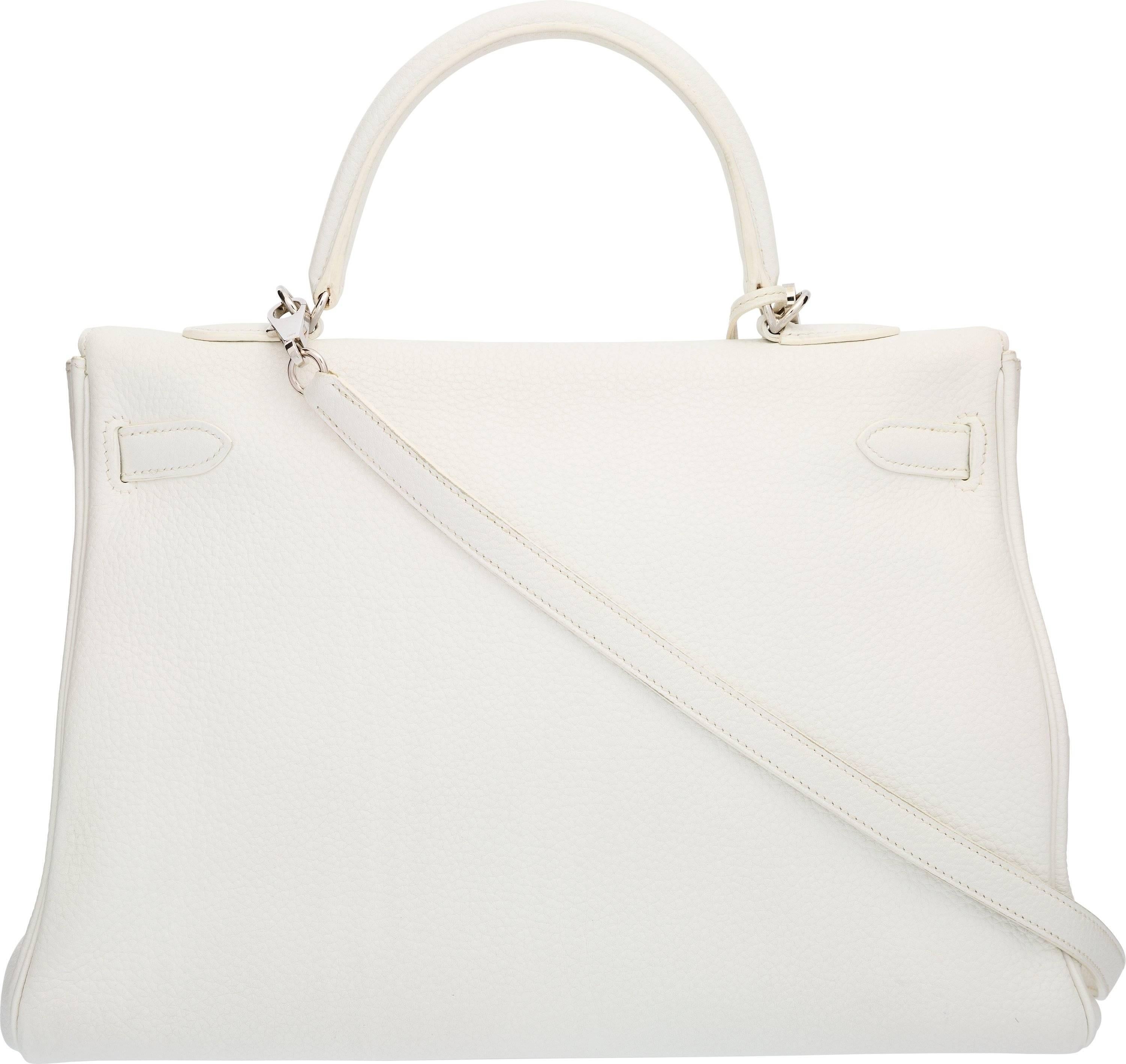 This Kelly bag is done in White Clemence Leather, featuring one top handle, one removable shoulder strap, Palladium Hardware, and a flap top with a turnlock closure. The interior is done in matching White Chevre Leather, featuring one zip pocket and