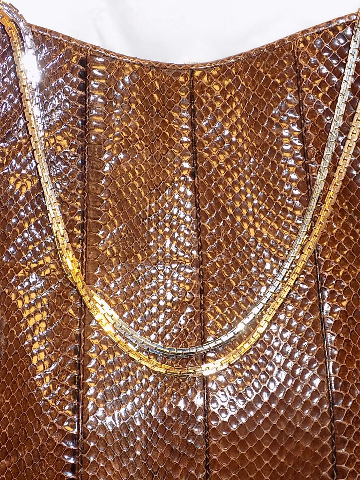 Beautiful  Judith Leiber Tote . The handbag is composed of a  brown snakeskin and features a  gold and silver tone  chain. There is a one interior zipper compartment and a snap closure. Leather lined  Comes with mirror and coin purse. This Bag  was