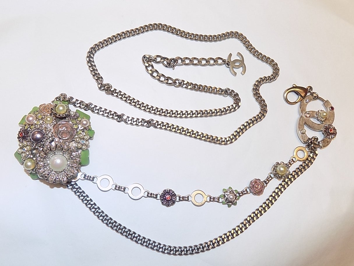 Made of enamel, pearls, crystals and glass stones with silver tone chains.  Wear this as a long necklace, choker or belt

Limited Edition Season 05P (2005)
The camellia has a 2.25 diameter.
It is made of enamel, pearls, glass stones and Austrian