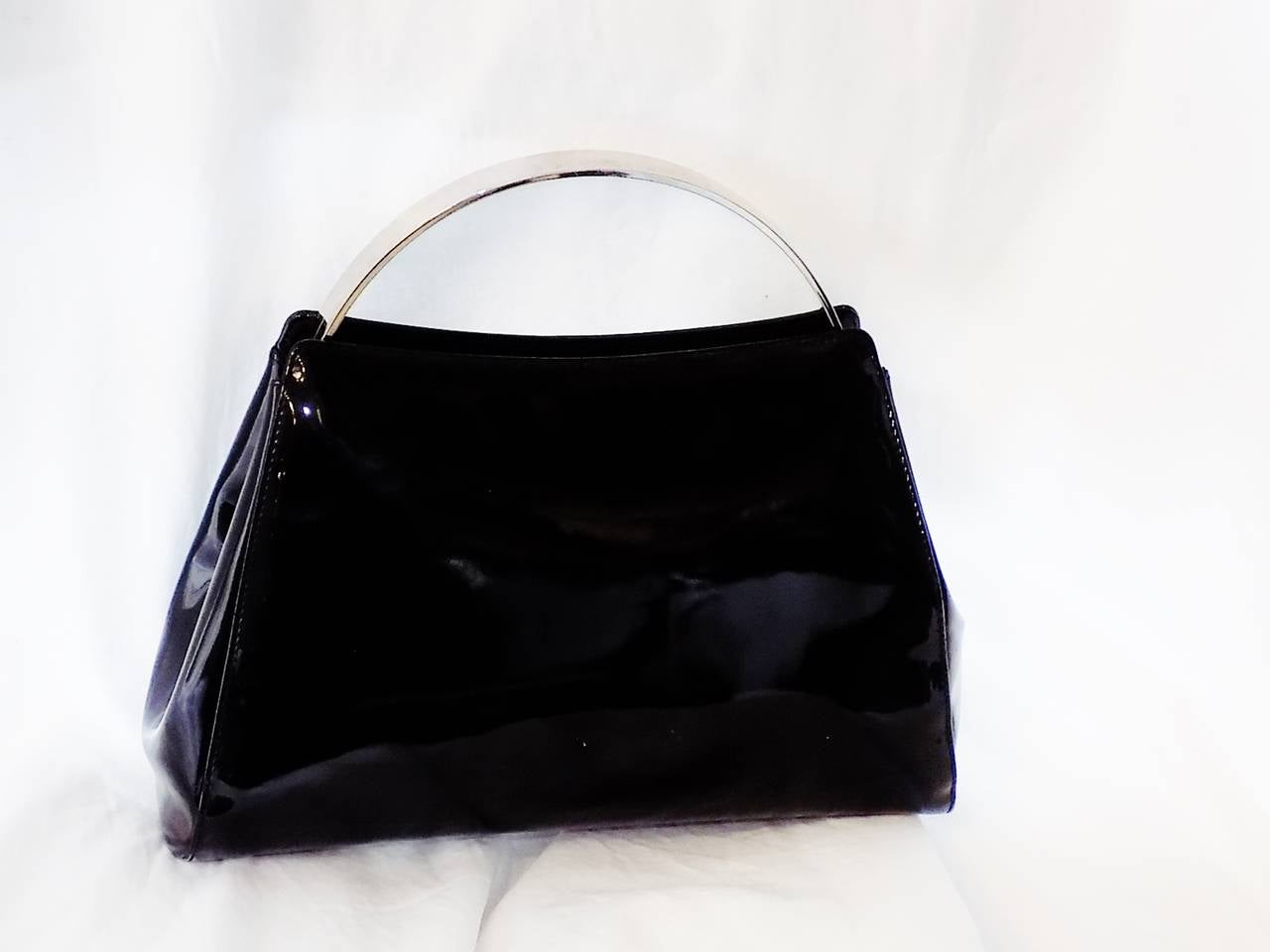 Beautiful Vintage black patent leather dinner bag. Silver hard frame with hard half moon handles featuring engraved CHANEL lettering. . CC logo at the front. 
Black leather lined with one inner zipper pocket and one side open pocket. Pristine