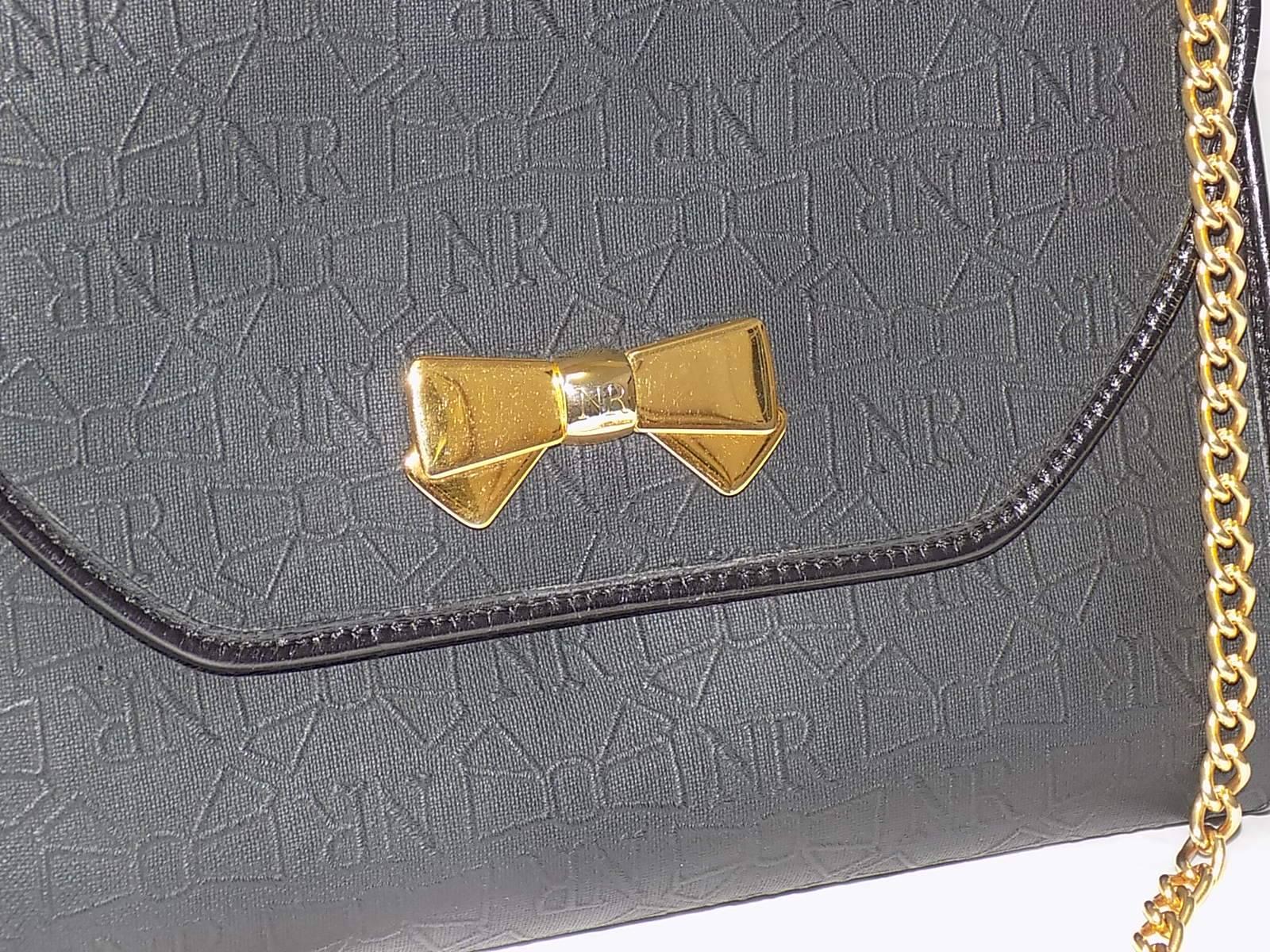 Nina Ricci black coated canvas with leather trims Gold Chain shoulder bag convertible to clutch bag. Gold signature bow at the front. NR logo and bow imprint all over the bag. Leather trim. 
Measures  8