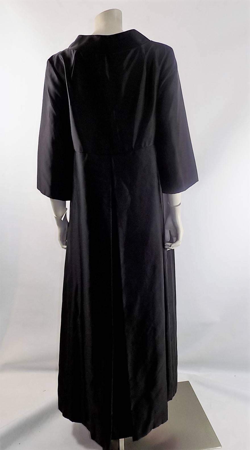 Floor length black satin in pristine condition like new. Wide  collar,  Empire cut with front bow  and 3/4 sleeves . Hidden snap closure. Fully lined. Amazing crisp look. So perfect over gown with gloves. 
Bust  38