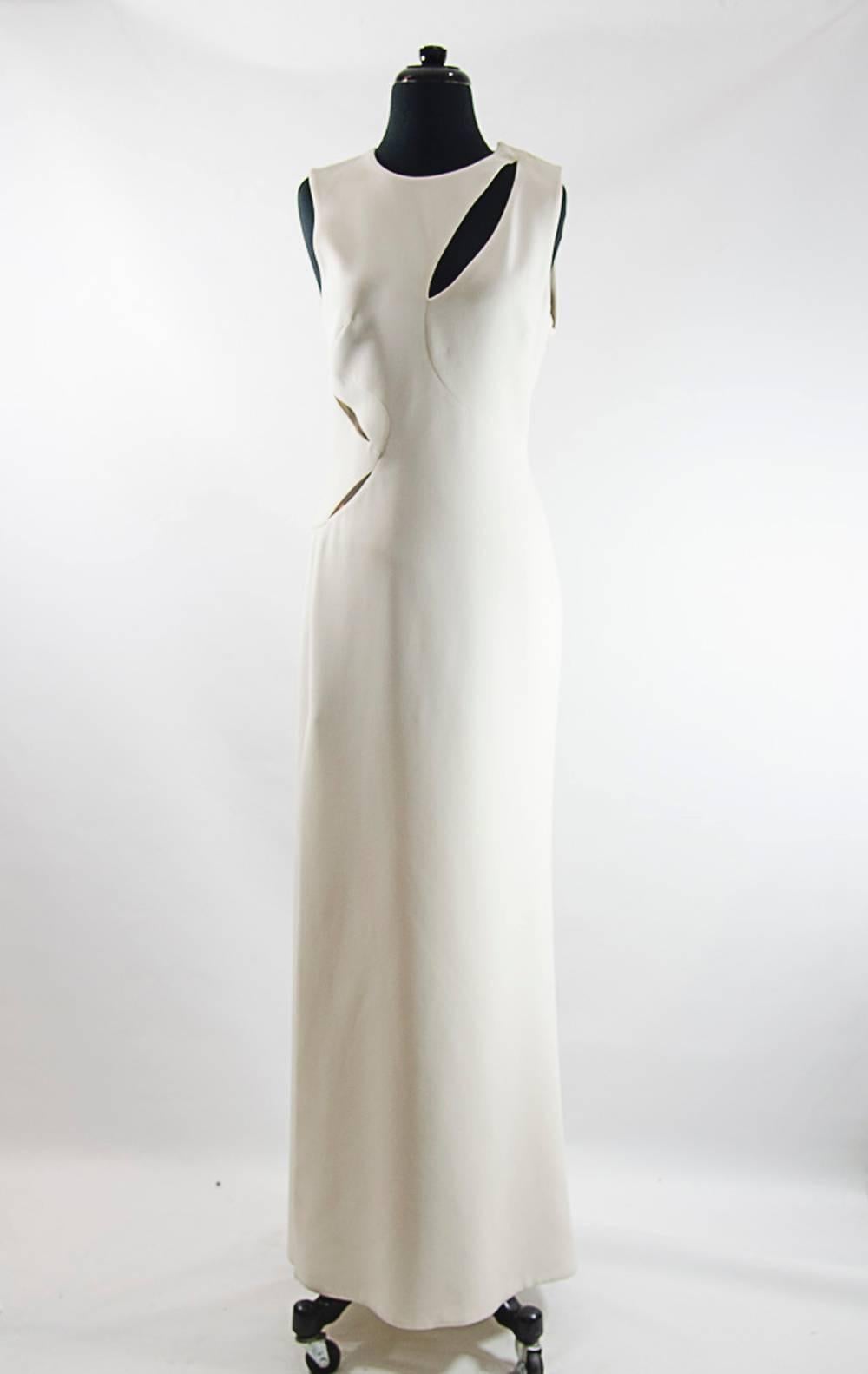 White silk-cady full-length sleeveless gown with cutout detailing at front, back and side. Versace gown has a thigh-high vent at side, round neck, flared skirt, is slightly fitted at the waist, has a concealed zip fastening at the side and is
